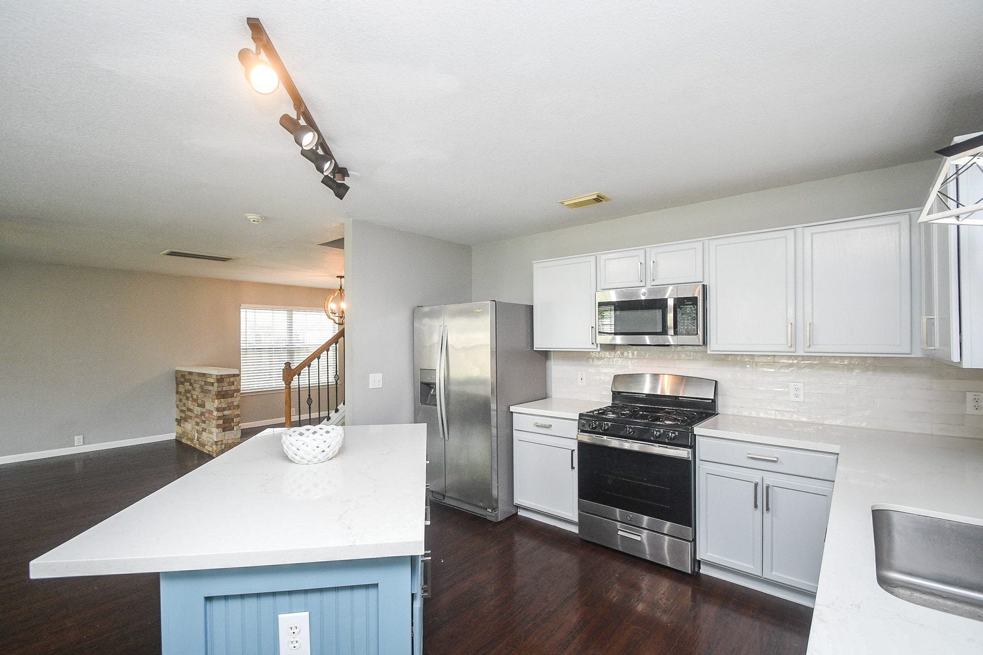10222 Antelope Alley, Missouri City, TX 77459 Bright, modern kitchen featuring stainless steel appliances, white cabinetry, and a sleek island with a contrasting blue base.
