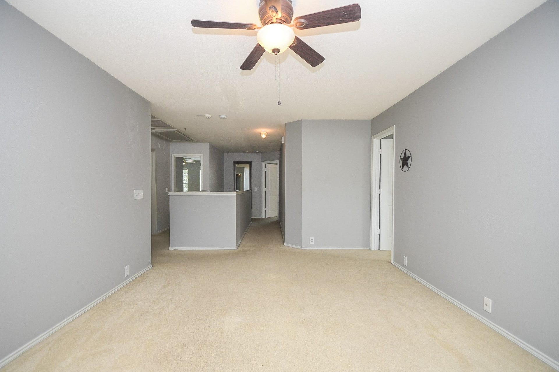 10222 Antelope Alley, Missouri City, TX 77459 Spacious living area with neutral tones, featuring a ceiling fan and ample natural light, leading to a cozy hallway.