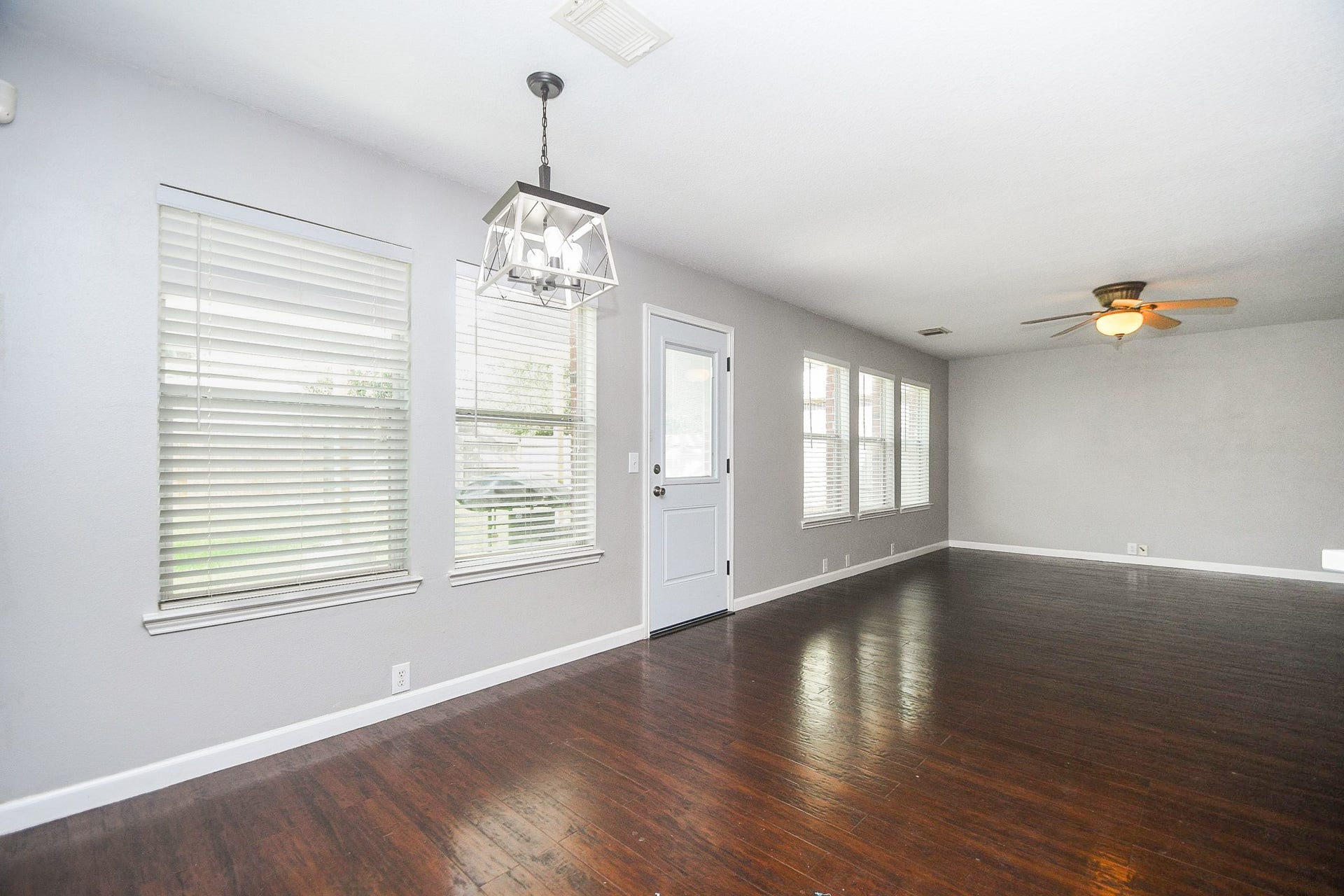10222 Antelope Alley, Missouri City, TX 77459 Spacious living area with rich hardwood floors, abundant natural light from multiple windows, and modern fixtures including a ceiling fan and stylish light fixture.