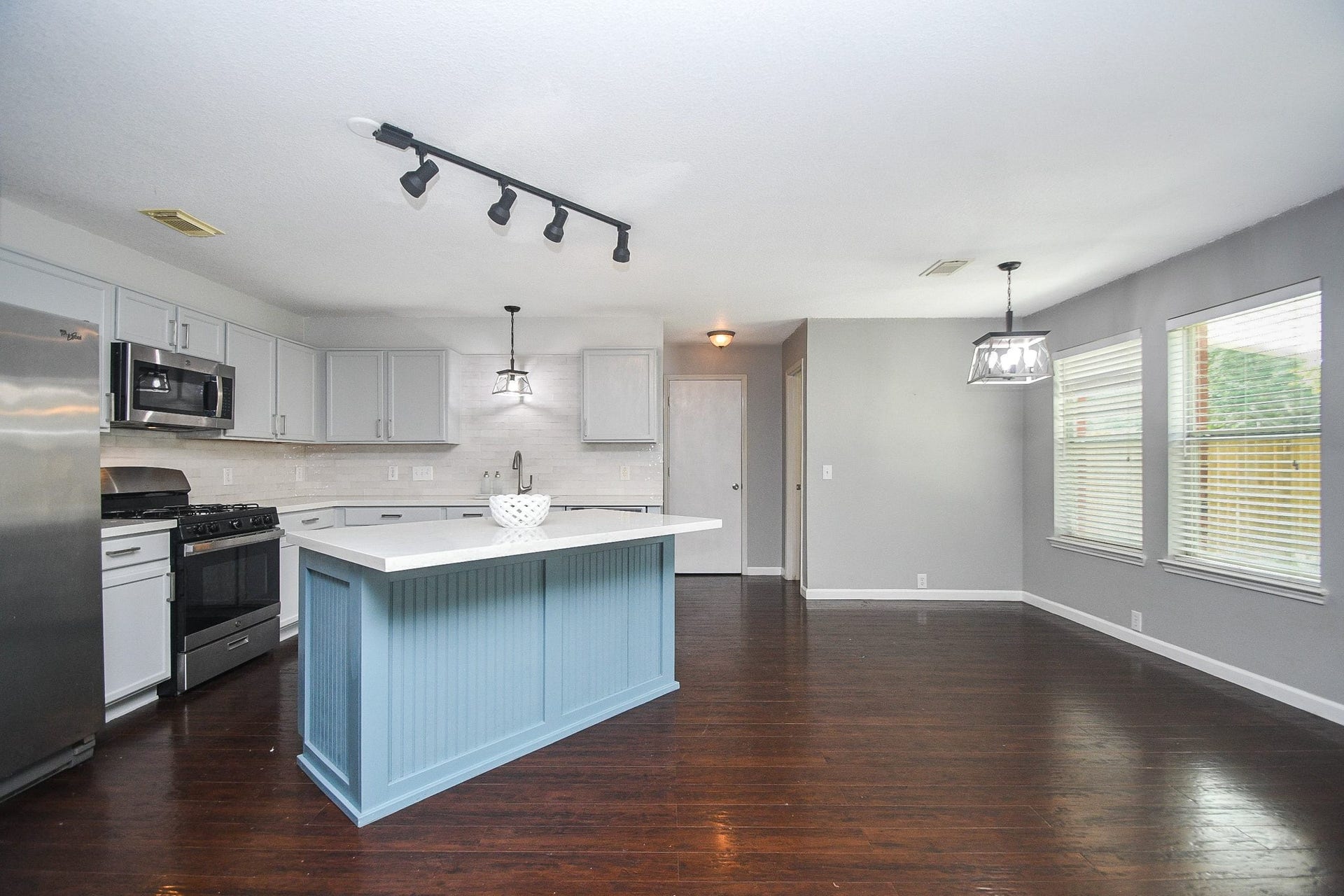 10222 Antelope Alley, Missouri City, TX 77459 Spacious kitchen with a stylish blue island, stainless steel appliances, and sleek cabinetry, seamlessly connecting to a bright dining area with ample natural light.