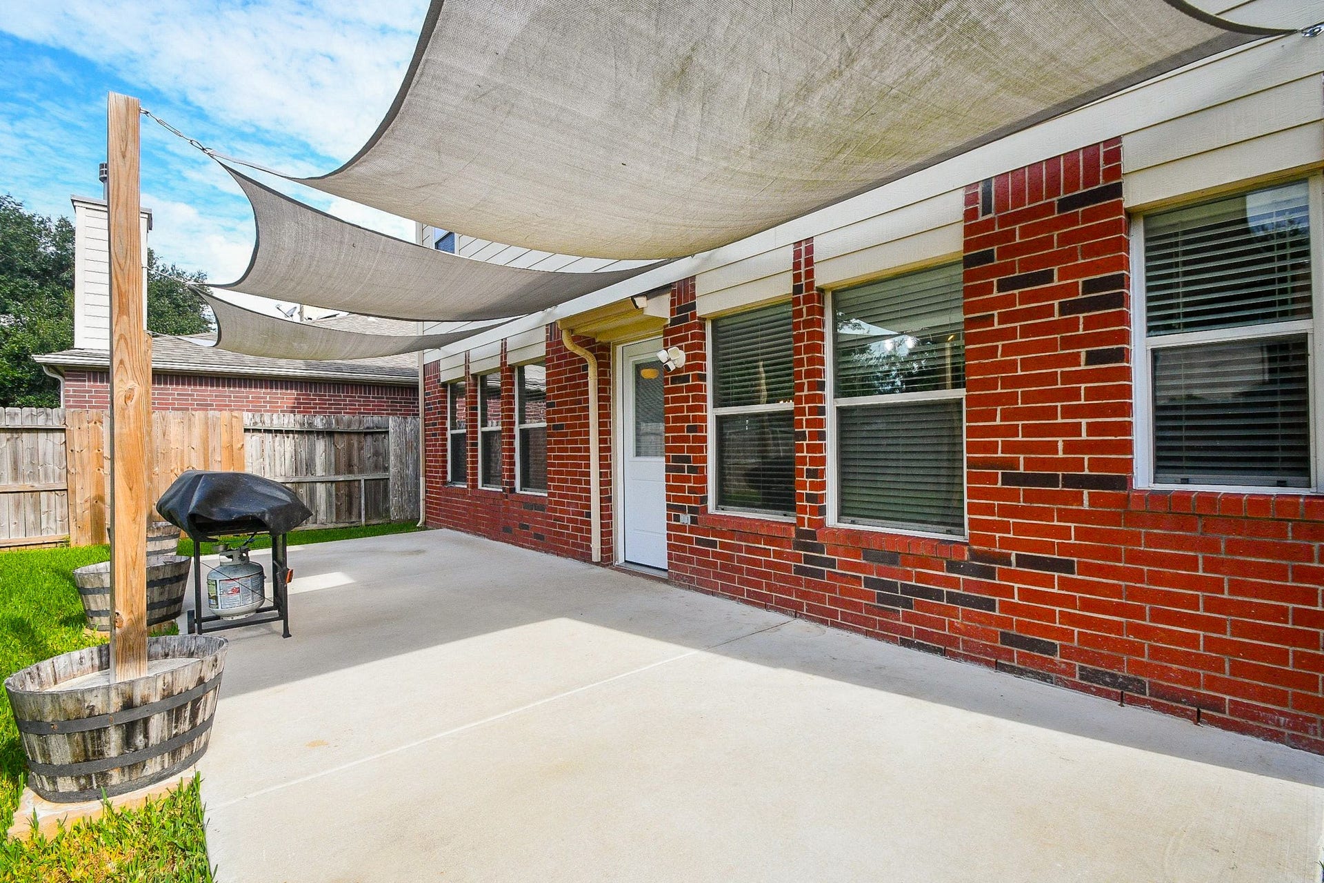 10222 Antelope Alley, Missouri City, TX 77459 Spacious backyard patio with stylish shade sails, perfect for outdoor grilling and relaxation.