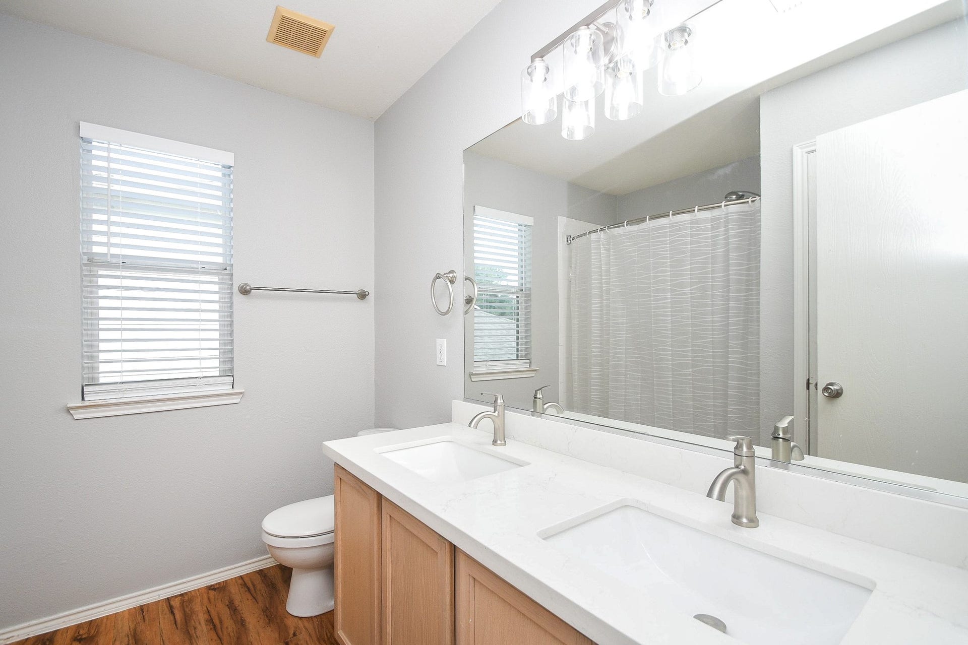 10222 Antelope Alley, Missouri City, TX 77459 Bright and inviting bathroom featuring a double vanity with a sleek, modern design, complemented by a large mirror and contemporary light fixtures.
