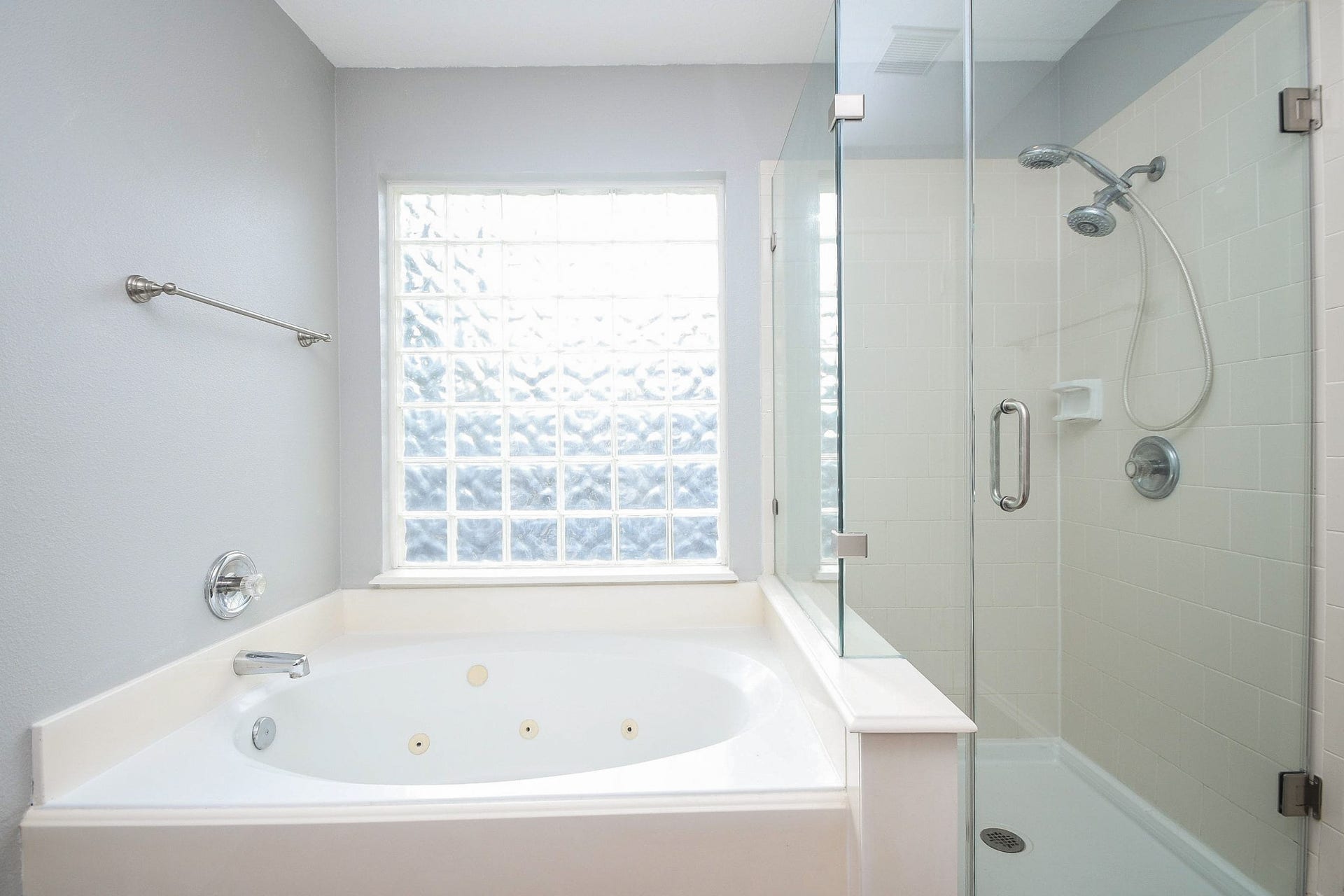 10222 Antelope Alley, Missouri City, TX 77459 Bright bathroom featuring a luxurious jetted tub and a sleek glass-enclosed shower, complemented by a large frosted window for natural light and privacy.