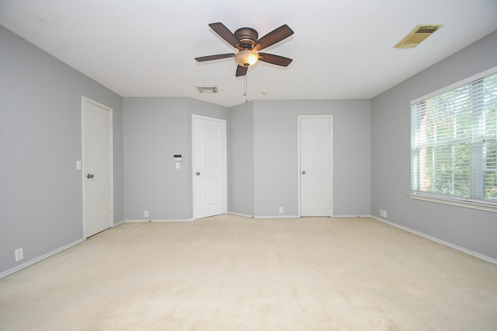 10222 Antelope Alley, Missouri City, TX 77459 Spacious bedroom with soft carpet, neutral walls, a ceiling fan, and abundant natural light from a large window.