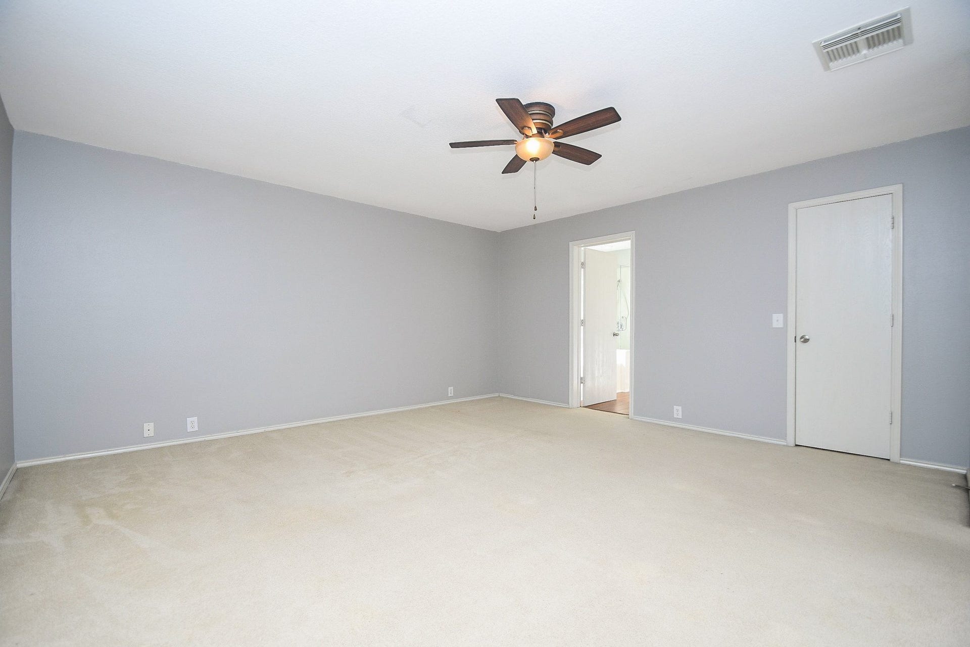 10222 Antelope Alley, Missouri City, TX 77459 Spacious bedroom with neutral carpeting, soft gray walls, and a ceiling fan, offering a welcoming atmosphere and ample natural light.