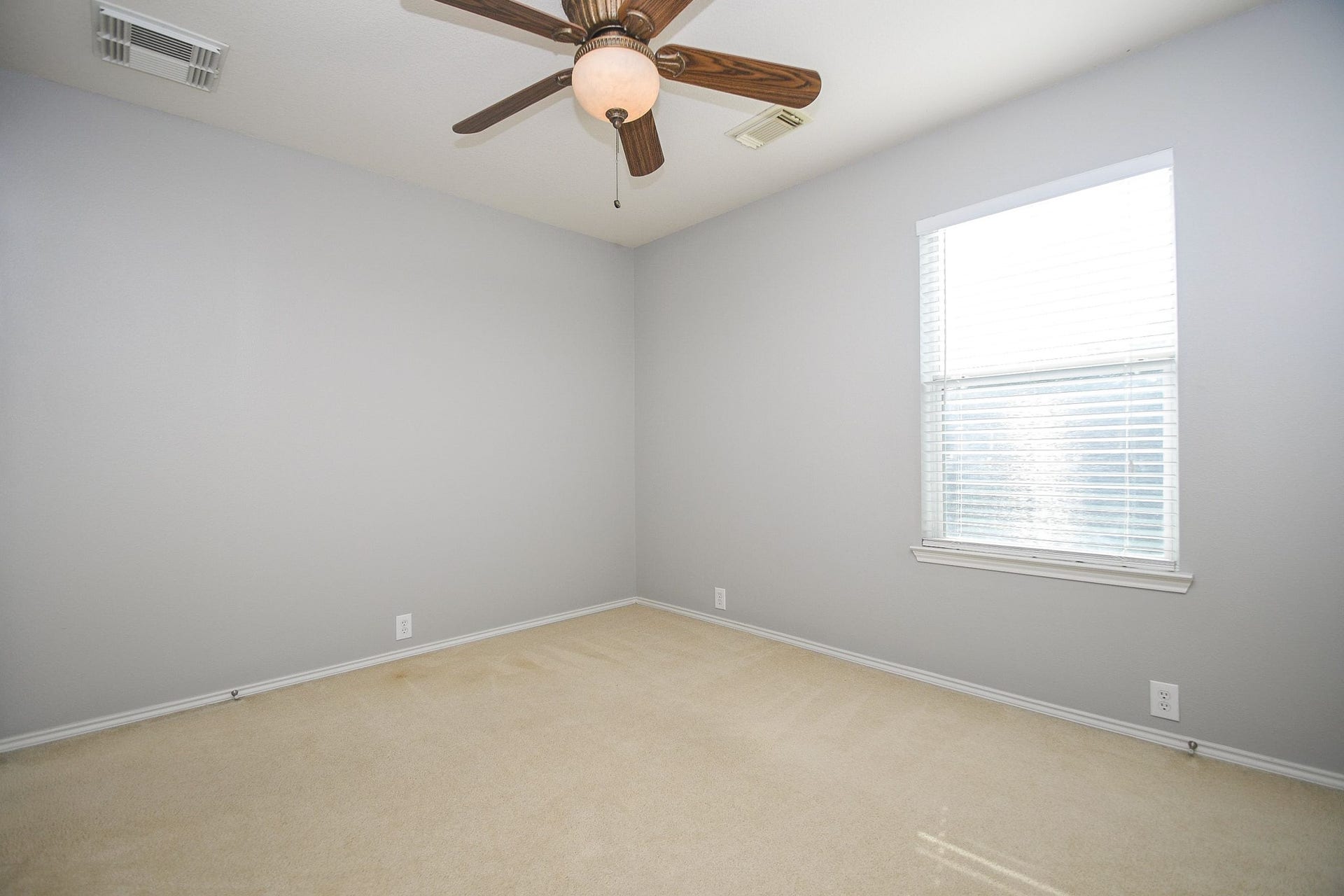 10222 Antelope Alley, Missouri City, TX 77459 Bright and inviting room with soft gray walls, a large window for natural light, and a ceiling fan for comfort.