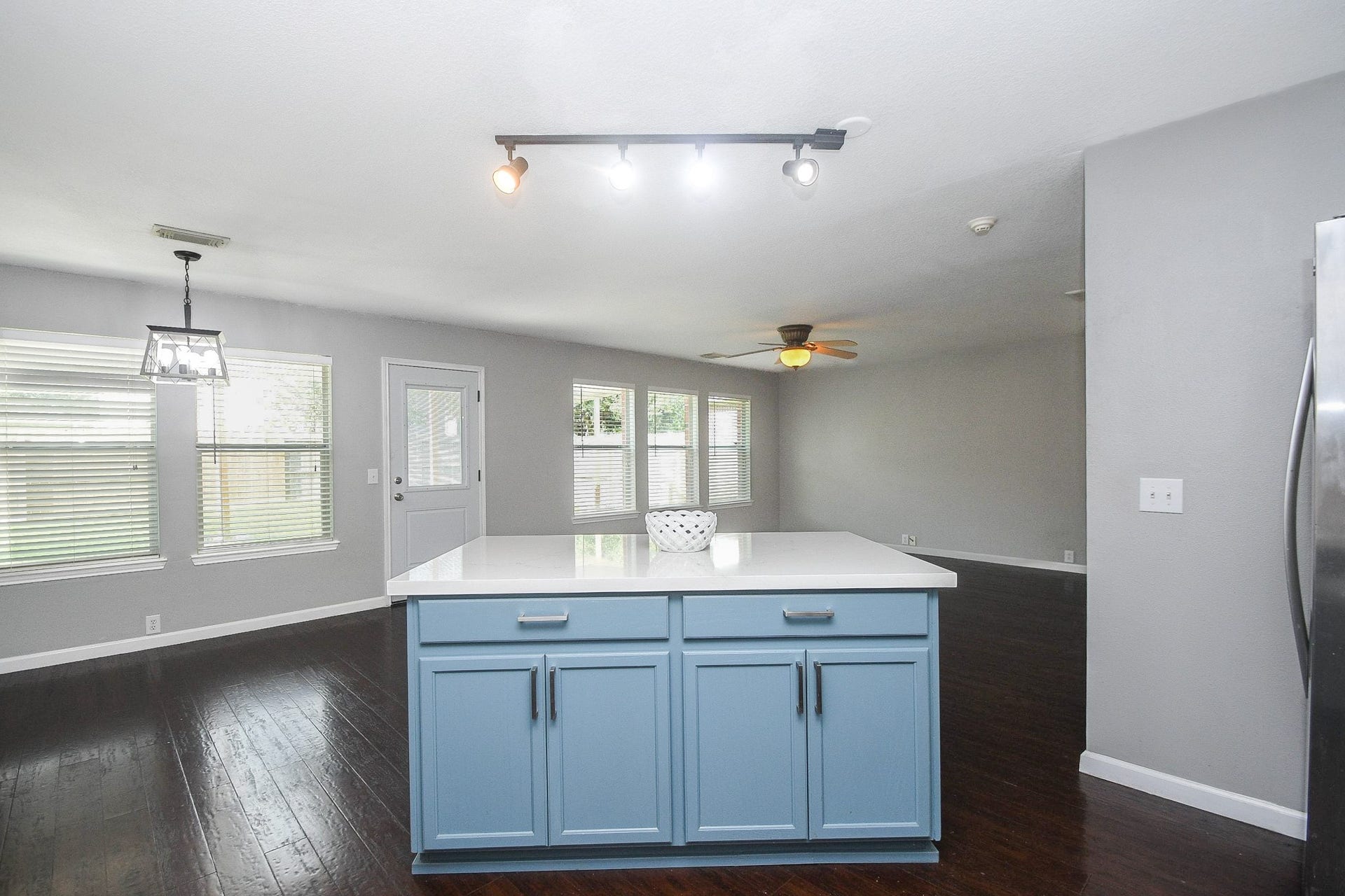 10222 Antelope Alley, Missouri City, TX 77459 Spacious open-concept living area featuring a modern kitchen island with a stylish blue base, ample natural light, and sleek hardwood floors.