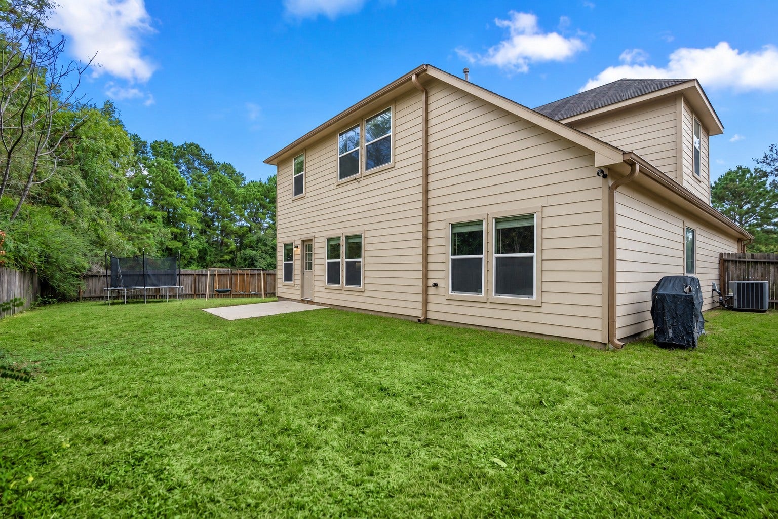 942 Oak Glen Drive, Conroe, TX 77378 This angle shows how much potential the backyard has, with open lawn wrapping around the home and no back neighbor behind it. Theres room to imagine a larger patio setup, garden beds, play space, or just a little more outdoor livingwhile the mature trees beyond the fence keep the view feeling open and green.