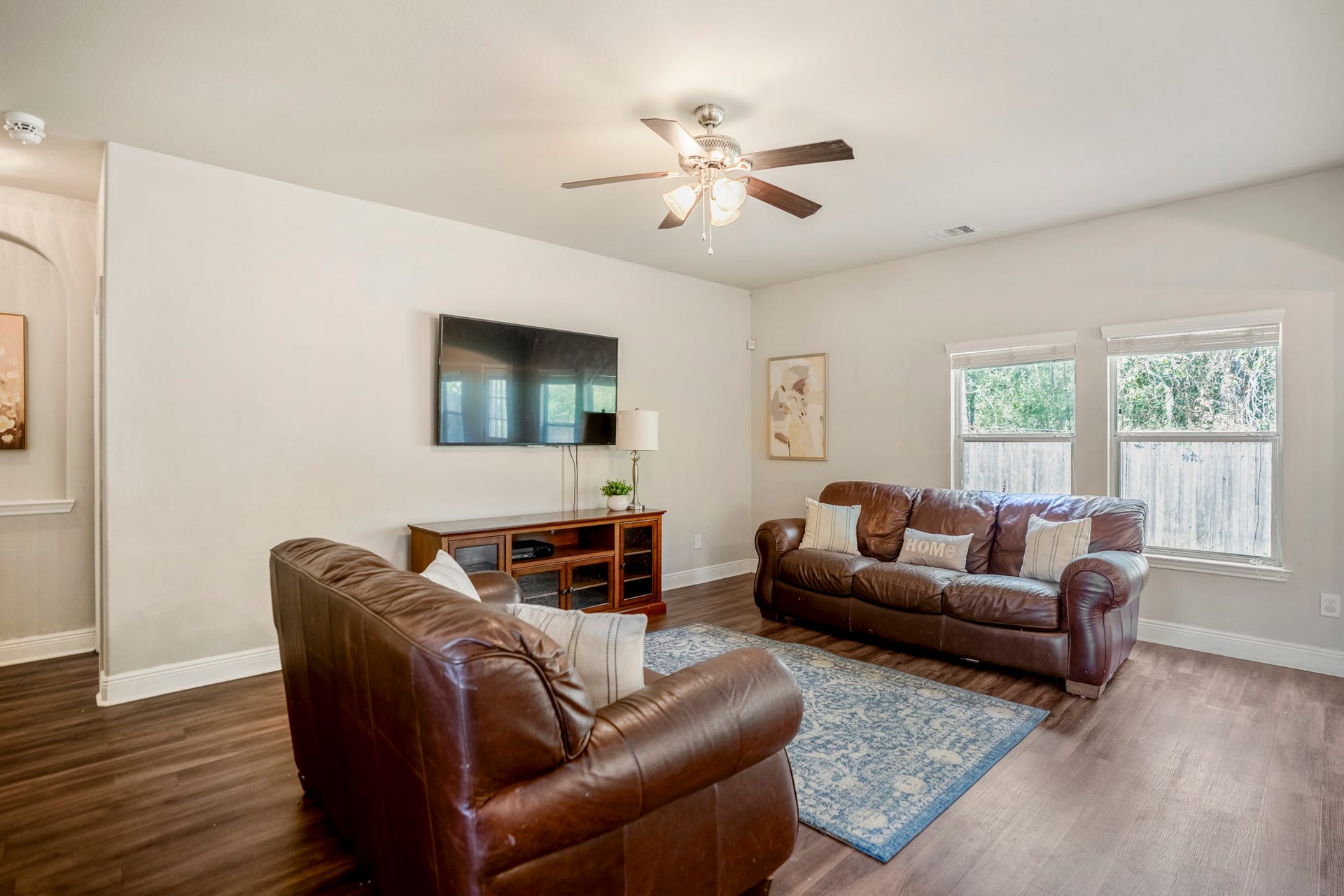 942 Oak Glen Drive, Conroe, TX 77378 Looking back across the living room, the windows along the rear wall keep the backyard in view, while the arched opening on the left leads into the hallway toward the downstairs primary suite. Its an easy layout for everyday lifethe living room stays connected to the kitchen and breakfast area, while the primary bedroom sits just far enough away to feel a little more removed from the activity.
