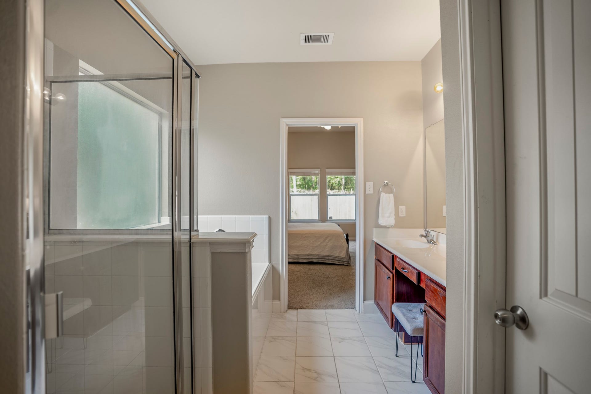 942 Oak Glen Drive, Conroe, TX 77378 Looking back through the primary bath, the shower sits to the left with the dual vanity running along the opposite side. Straight ahead, the doorway leads back into the primary bedroom, making the whole suite feel connected and easy to move through from one space to the next.