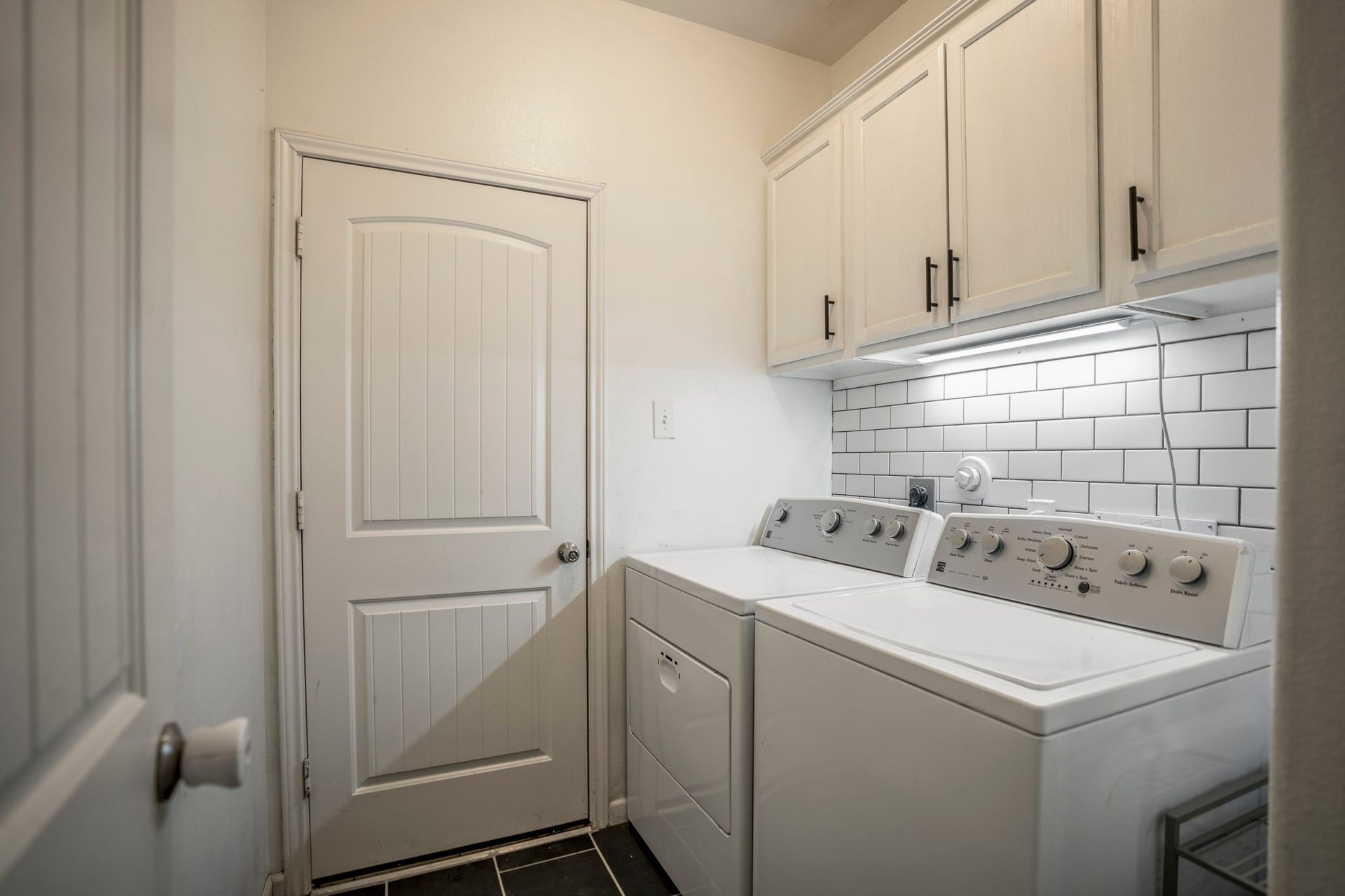 942 Oak Glen Drive, Conroe, TX 77378 Back downstairs, the utility room keeps laundry and storage tucked into their own space just off the main hall. Built-in cabinetry, under-cabinet lighting, and a subway tile backsplash give the room a finished look, while new tile flooring keeps it practical for everyday use. The door ahead leads directly into the garage, making this an easy drop zone for coming and going.