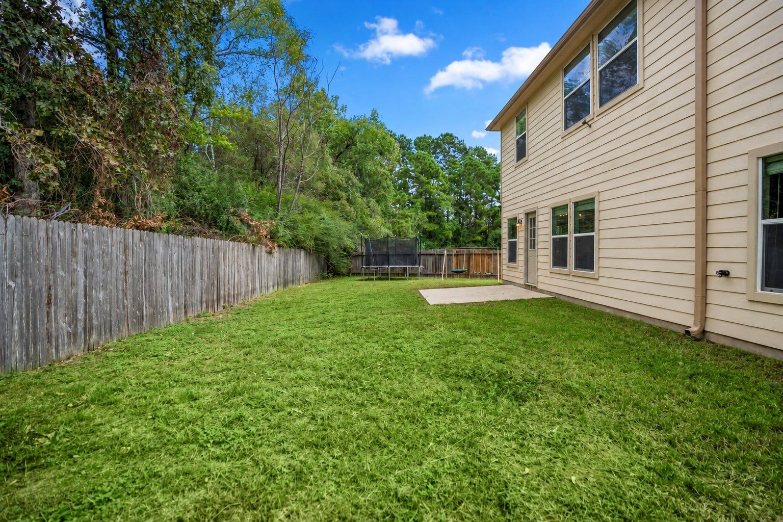 942 Oak Glen Drive, Conroe, TX 77378 Stepping back from the patio, you get a better sense of how much lawn stretches behind the home. The open space gives the backyard room to grow with future outdoor seating, play space, or landscaping, while the no-back-neighbor setting keeps the view feeling more open.