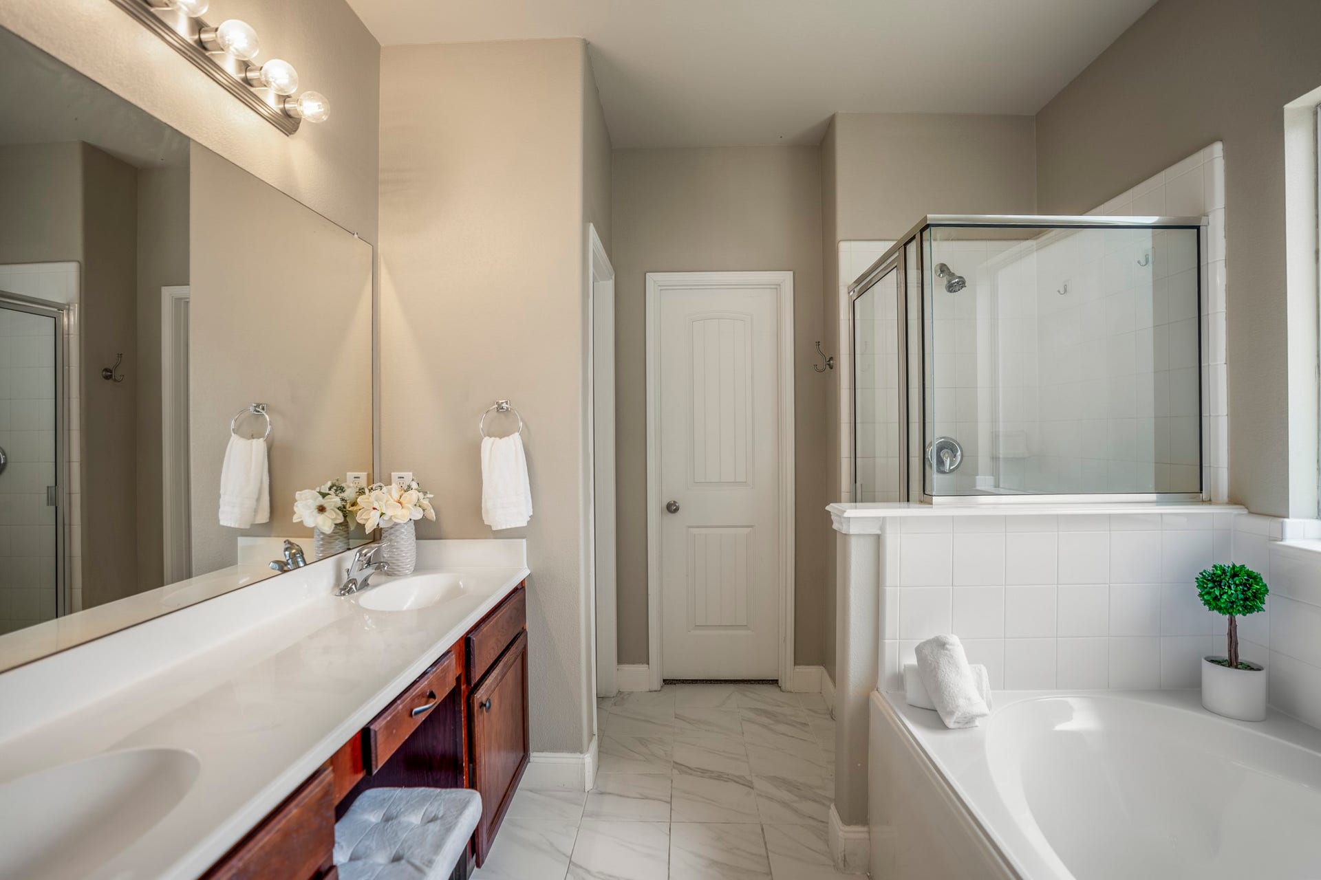 942 Oak Glen Drive, Conroe, TX 77378 Step into the primary bath, where dual sinks are separated by extra counter space and a seated vanity area that makes the morning routine feel a little more functional. The soaking tub and separate shower line the opposite side, while new tile flooring runs throughout. Straight ahead, the door leads into the walk-in closet, while the doorway just to the left is the toilet.