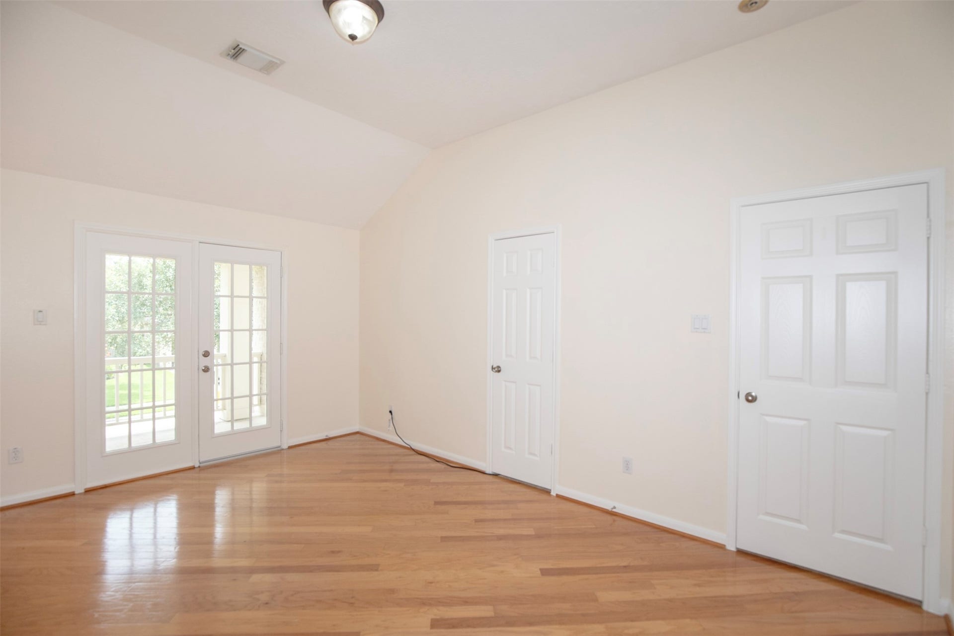 3612 Fir Hollow Way, Pearland, TX 77581 Spacious secondary bedroom offers wood flooring, vaulted ceilings, and direct access to a private balcony overlooking the neighborhood, adding charm and flexibility to this unique space.