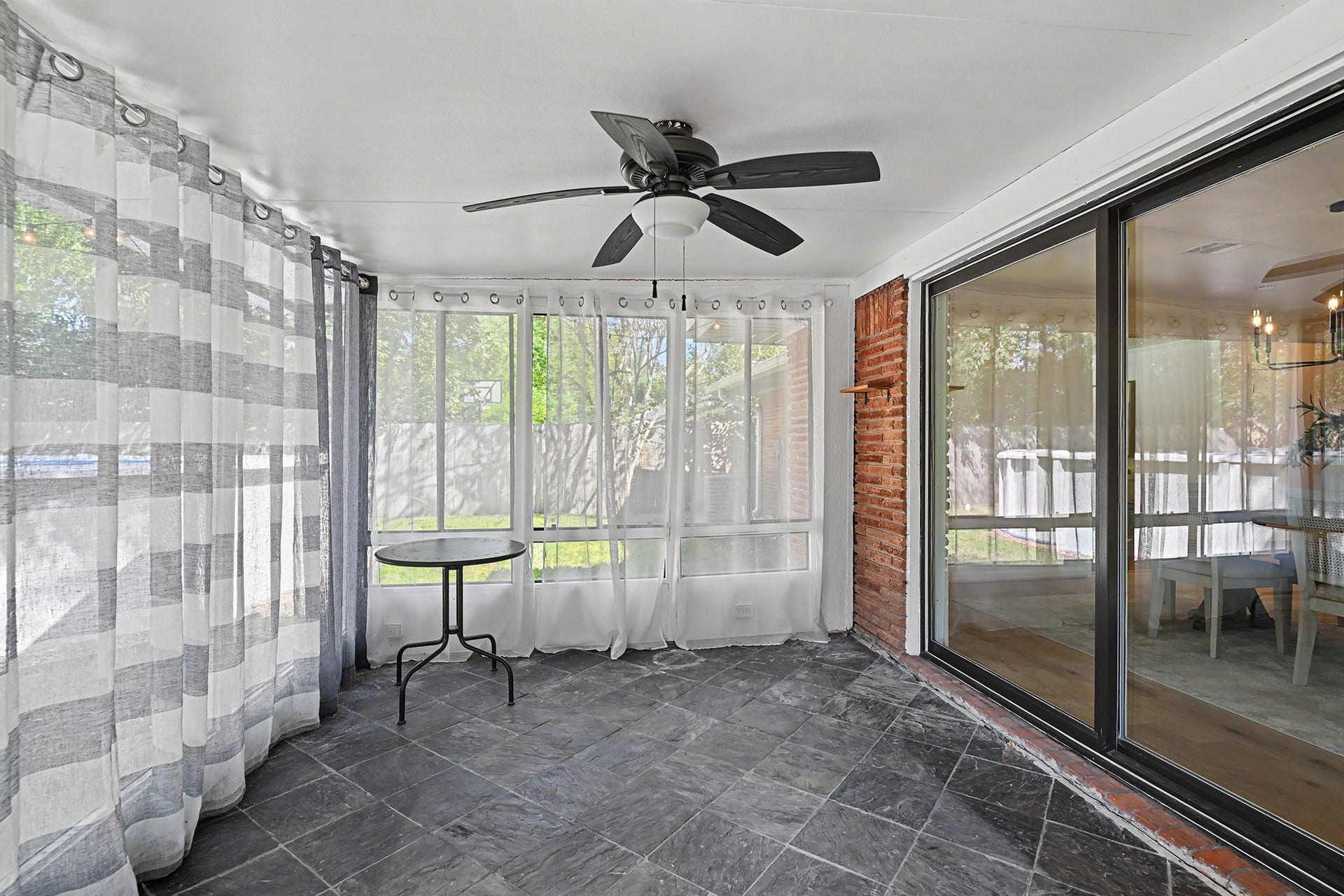 Functional and sunny closed-in porch with ceiling fan and window unit