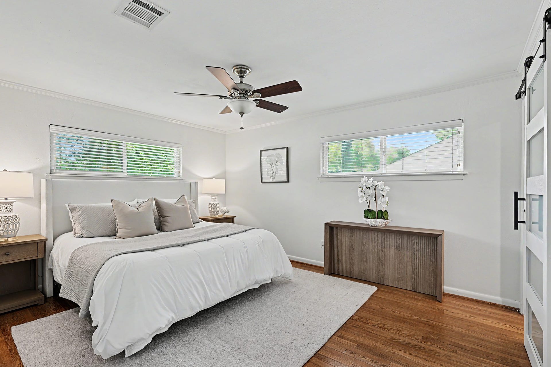 Primary bedroom with two windows, hardwood floors and ensuite bath
