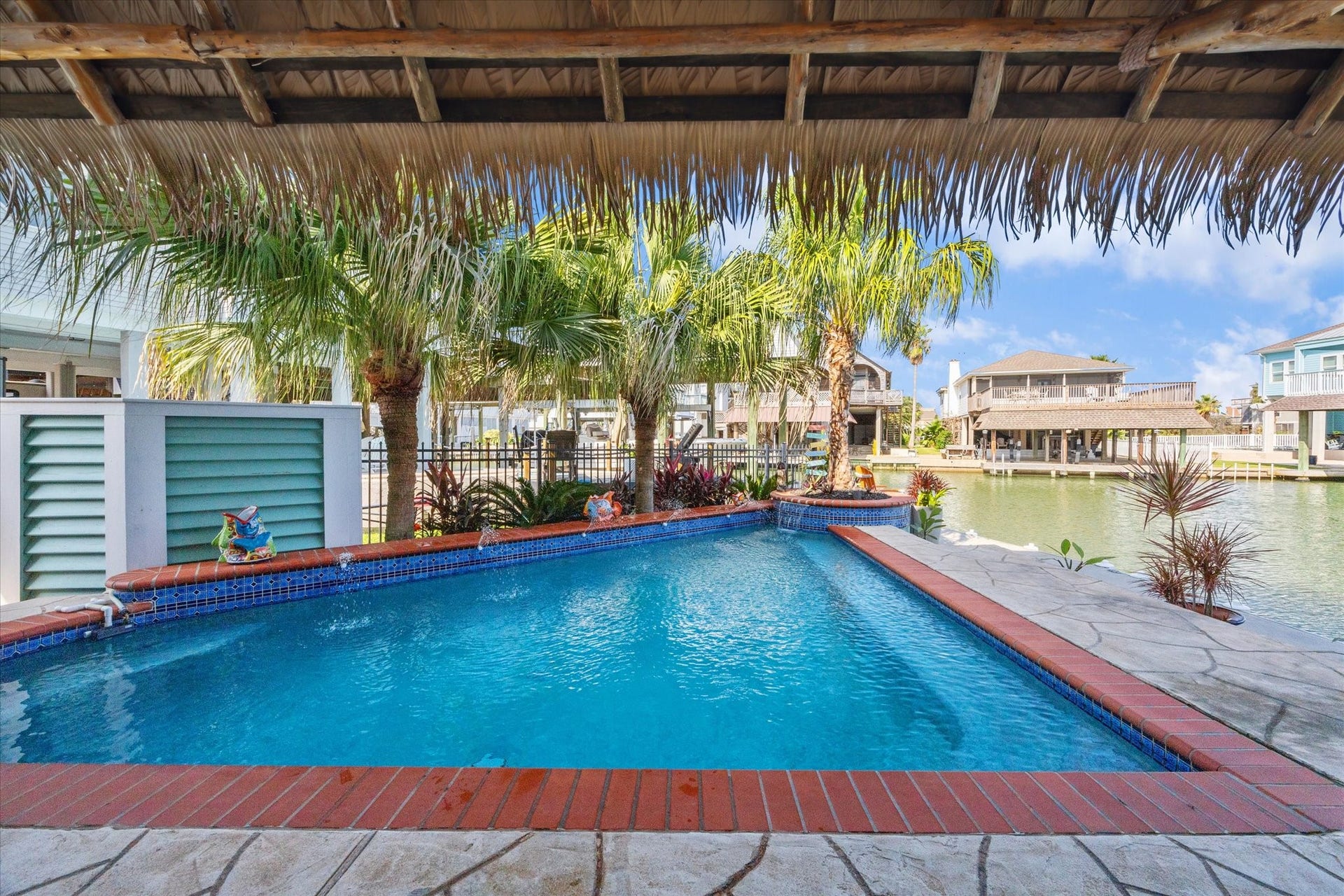 102 Bamaku Bend, Tiki Island, TX 77554 Welcome to your outdoor oasis with a heated pool overlooking the water, lushious landscaping, 118' of concrete bulkhead with bumper guards, 2 covered boat slips with lifts, tiki bar, synthetic palapa covering, 150 gallon bait well, stainless fish cleaning station with sink, ground level half bath, 4 garages and so much more!