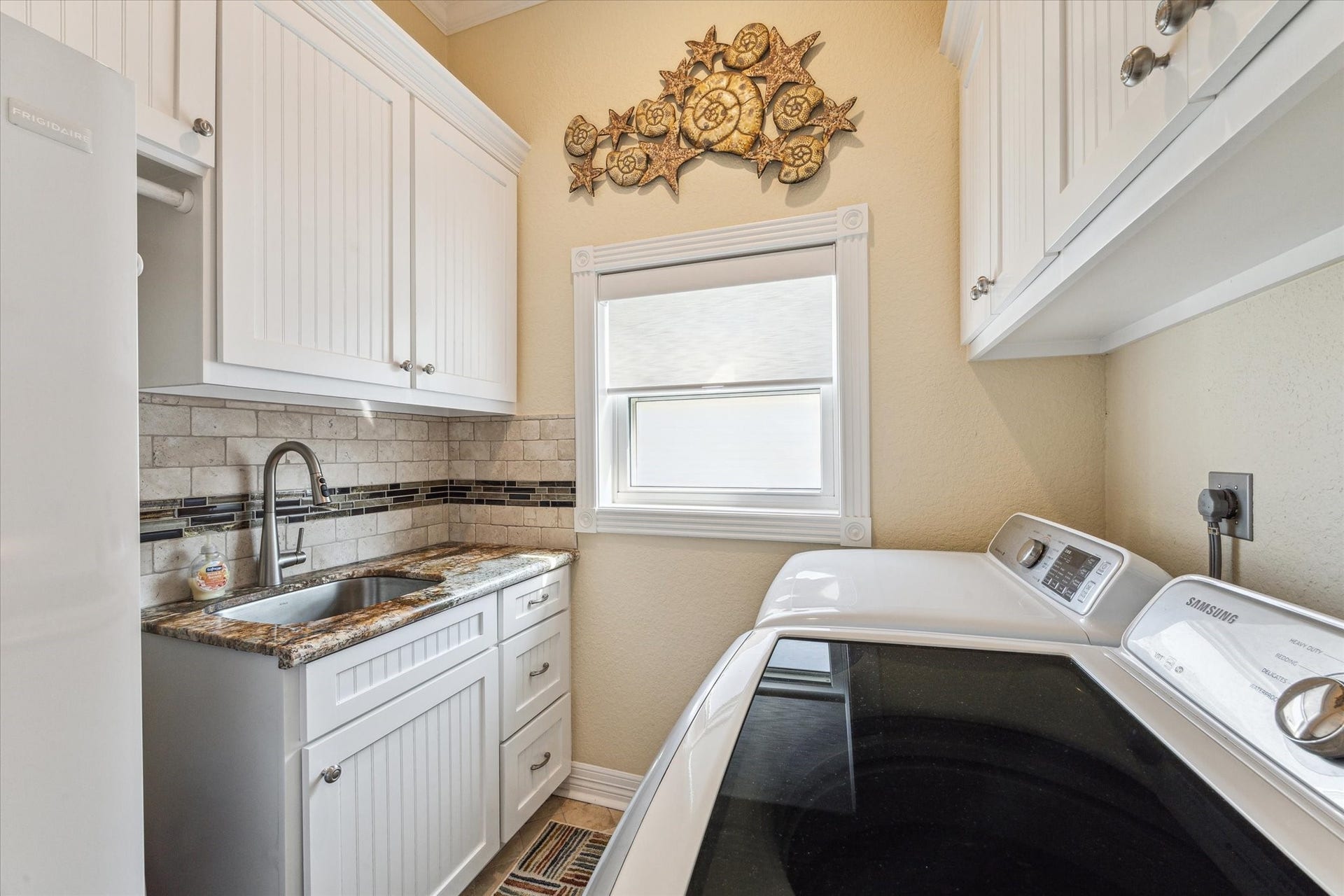 102 Bamaku Bend, Tiki Island, TX 77554 The laundry room was designed with ample custom cabinetry, a sink with granite counters, and room for an additional refrigerator.