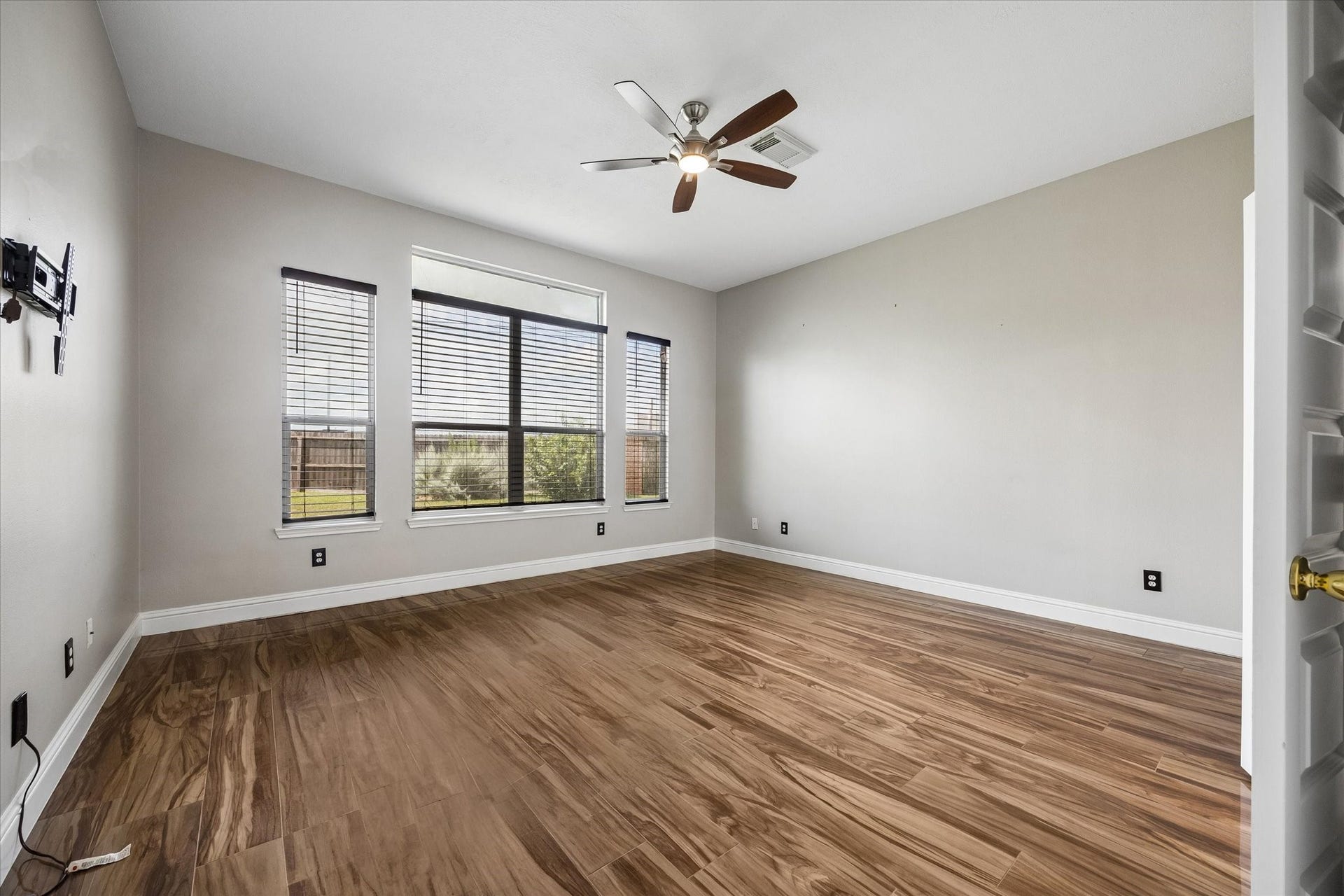 8422 W W Sienna Cove Lane Lane, Houston, TX 77083 Primary Bedroom: Spacious retreat featuring beautiful wood-look flooring, a ceiling fan, and large windows offering abundant natural light.