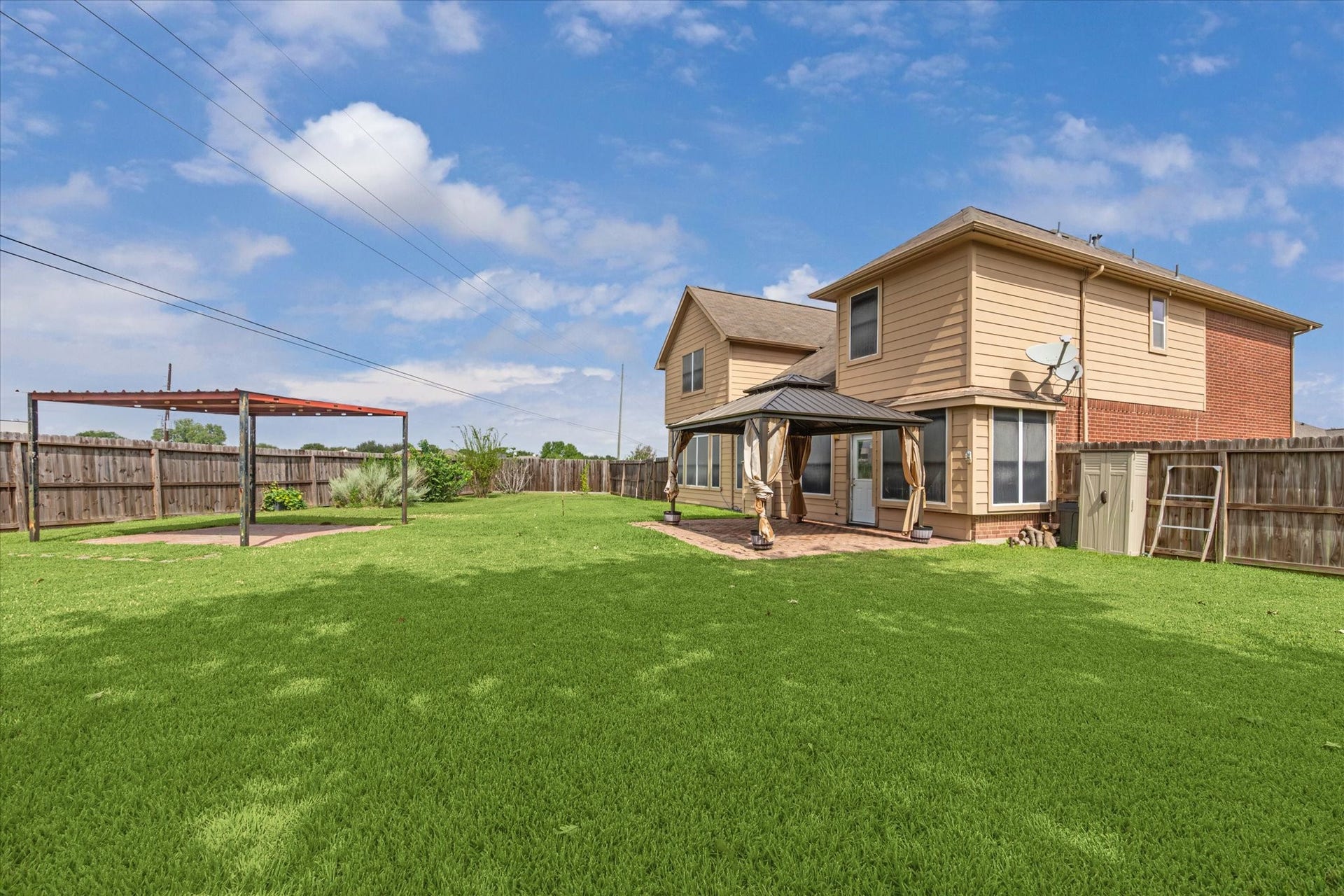 8422 W W Sienna Cove Lane Lane, Houston, TX 77083 Rear Exterior: Spacious backyard showcasing the home's two-story brick exterior, covered patio, and expansive lawn ideal for outdoor entertaining.