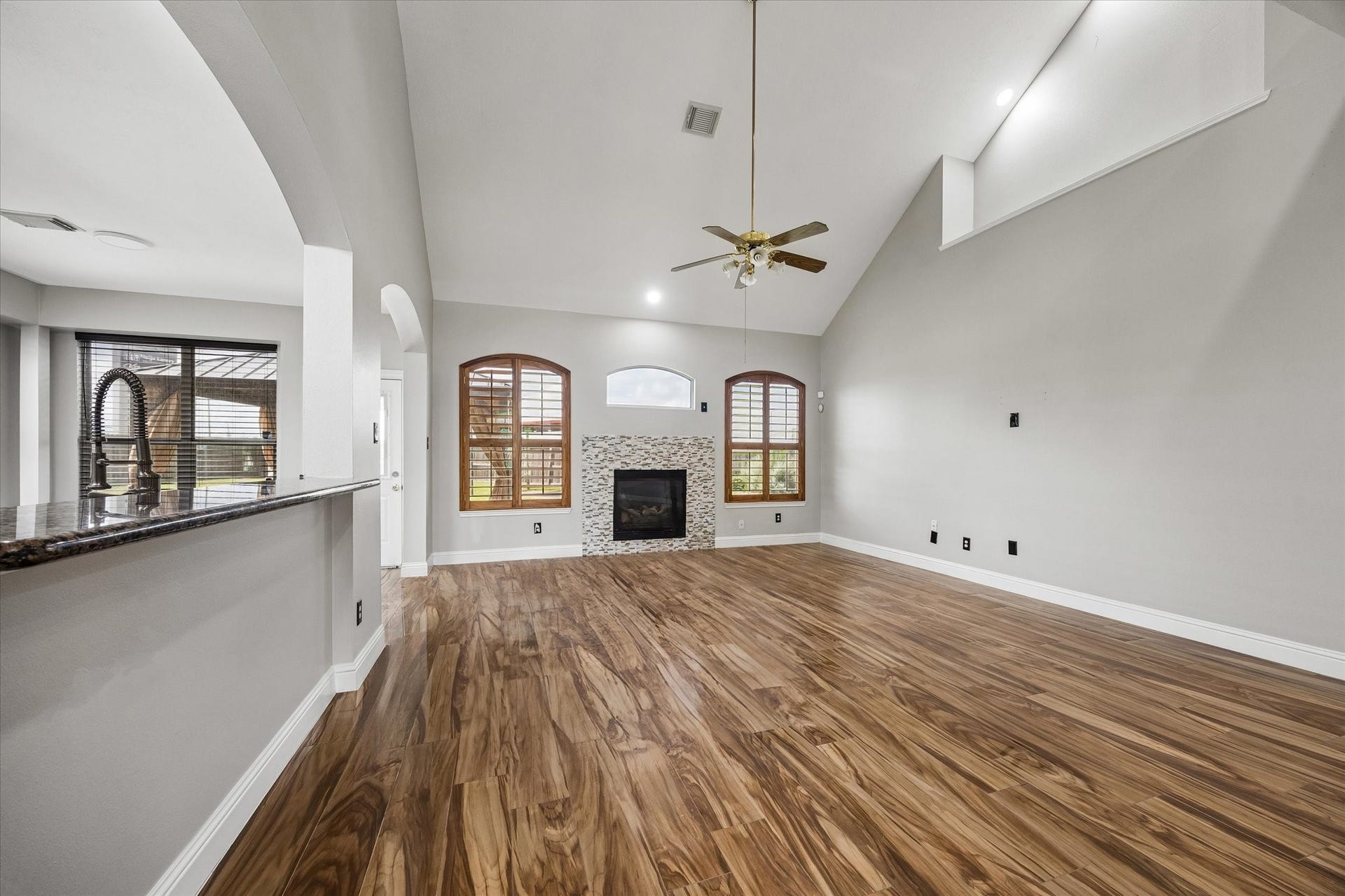 8422 W W Sienna Cove Lane Lane, Houston, TX 77083 Family Room: Expansive living area featuring soaring ceilings, glossy wood-look tile flooring, and a beautiful fireplace framed by windows.