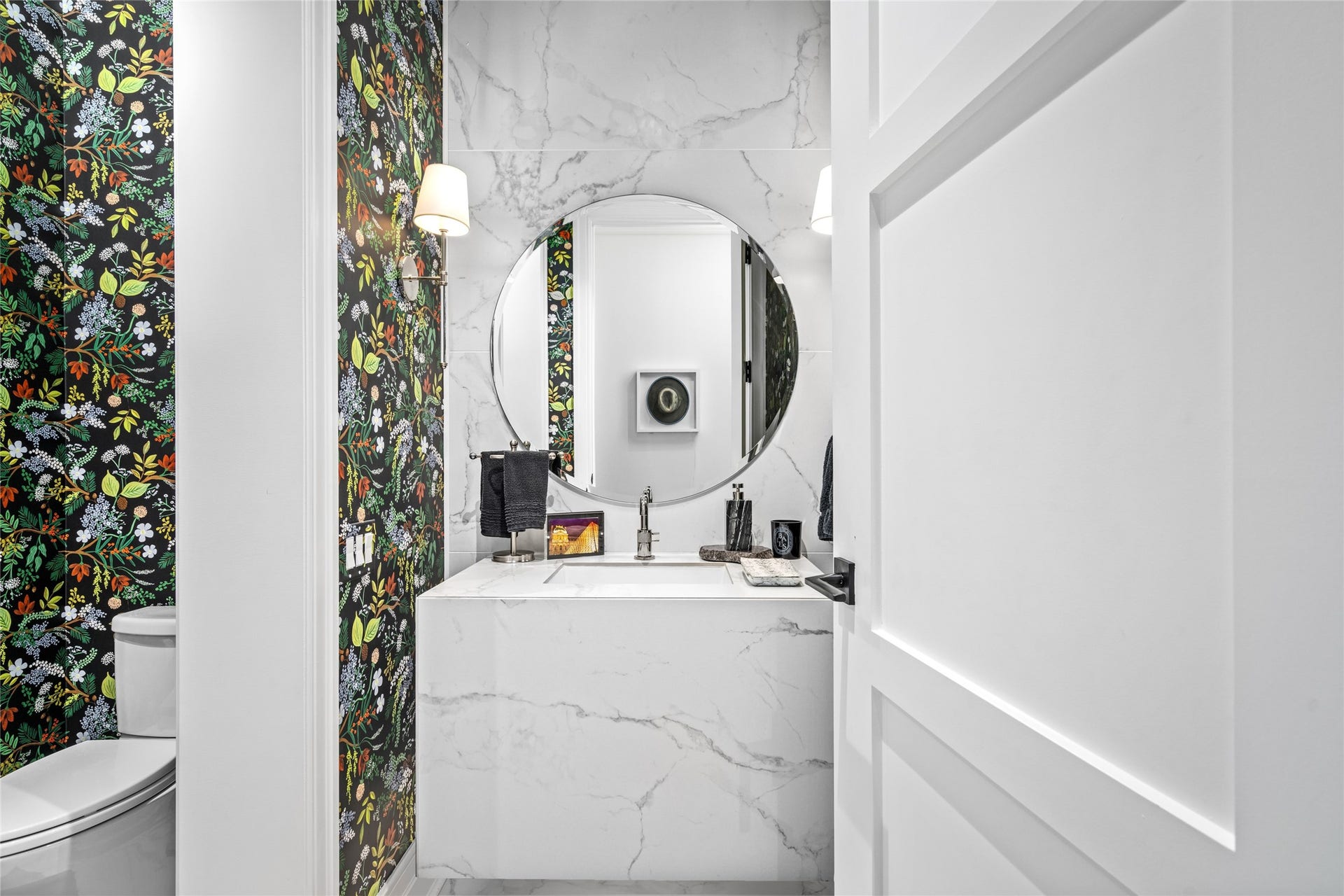 6017 Memorial, #202, Houston, TX 77007 This chic powder room features porcelain tile floors and accent wall, a backlit floating vanity paired with a circular
beveled mirror, chrome fixtures with shaded chrome sconces, and stylish decorative wallpaper for an eye catching
elegant focal point.