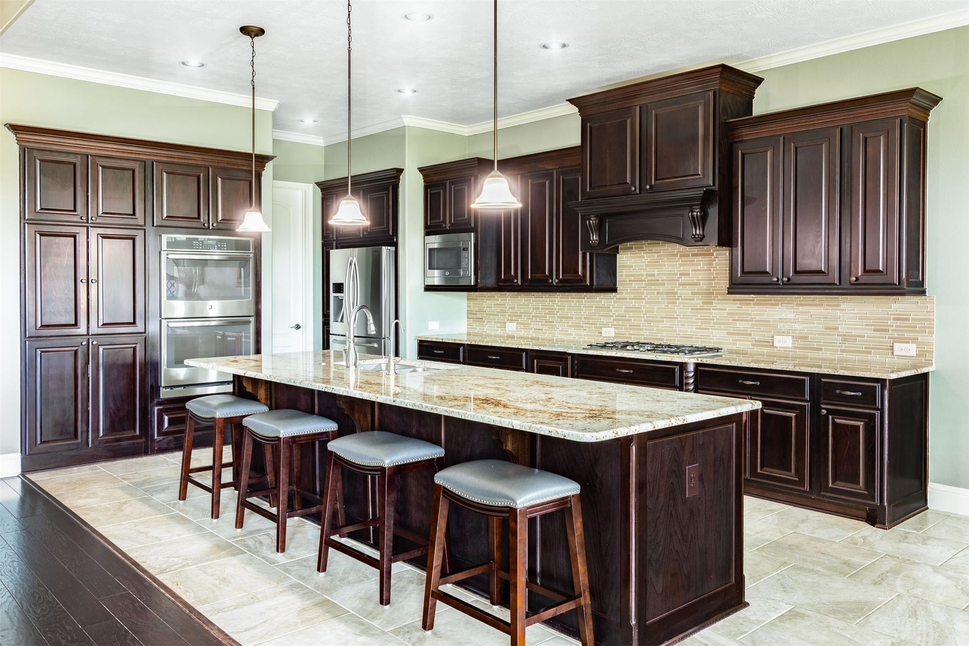 27506 Lakeway Trail Lane, Fulshear, TX 77441 Beautiful raised-panel cabinetry with substantial crown detailing brings warmth and distinction to the spacious kitchen. Granite counters, a shimmering tile backsplash, stainless steel double ovens and a gas cooktop surround the oversized island, creating an inviting space for cooking and gathering.