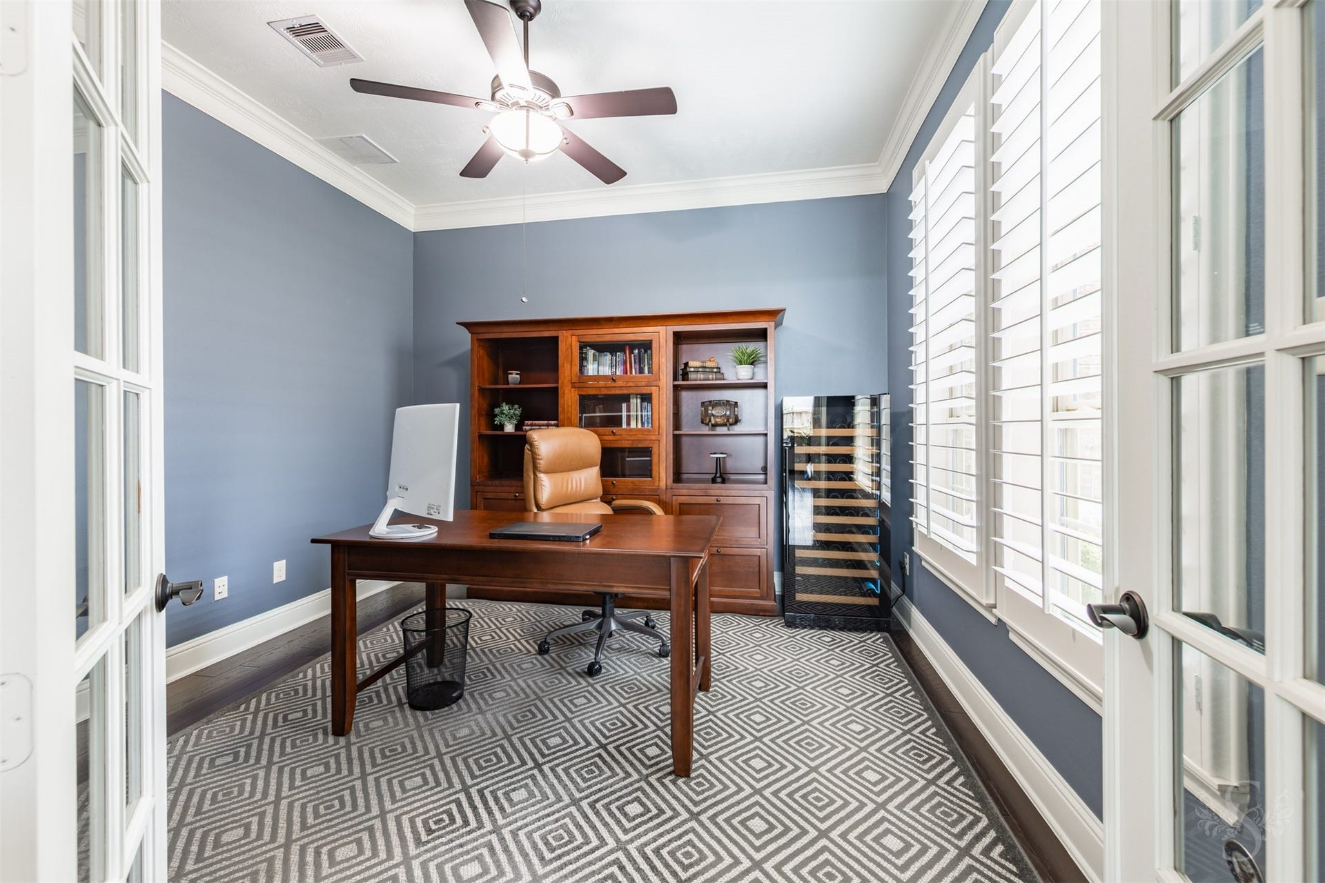 27506 Lakeway Trail Lane, Fulshear, TX 77441 Framed by French doors, the private study pairs rich wood flooring with soft blue walls and crisp crown molding. Expansive windows with plantation shutters create an inviting setting for working from home or enjoying a quiet read.