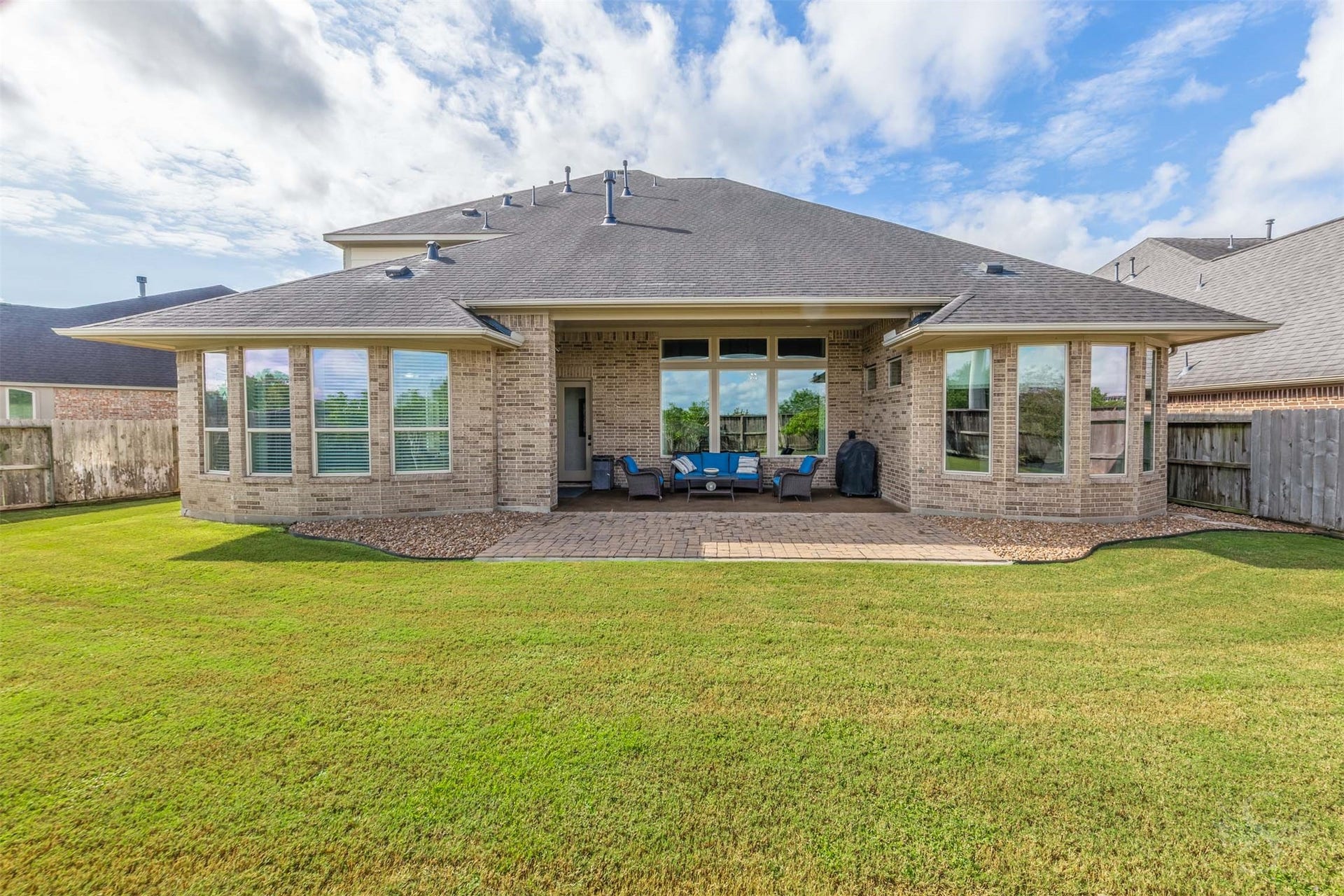 27506 Lakeway Trail Lane, Fulshear, TX 77441 The homes impressive rear elevation pairs graceful bay windows with a covered outdoor retreat overlooking the backyard. Gather beneath the patios shelter or enjoy dinner on the extended paver terrace, with plenty of green space beyond.