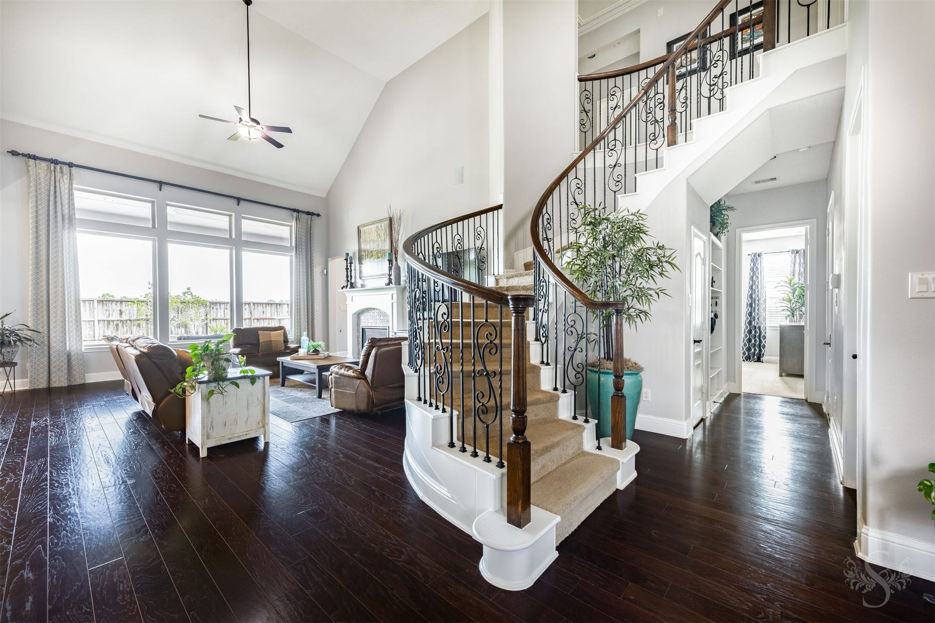 27506 Lakeway Trail Lane, Fulshear, TX 77441 A sweeping curved staircase with decorative iron balusters and a rich wood handrail creates a stunning architectural centerpiece. Beautiful wood flooring leads into the family room, where expansive windows and a dramatic ceiling height enhance the open design.