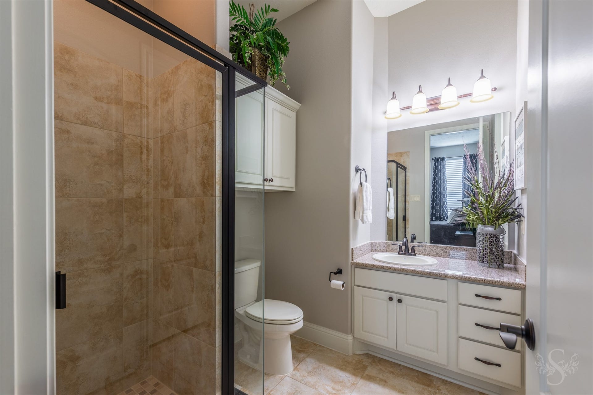27506 Lakeway Trail Lane, Fulshear, TX 77441 A crisp white vanity with a granite countertop and dark hardware gives this secondary bath an elegant, timeless look. A glass-enclosed tiled shower and additional wall cabinetry provide everyday comfort and convenient storage.
