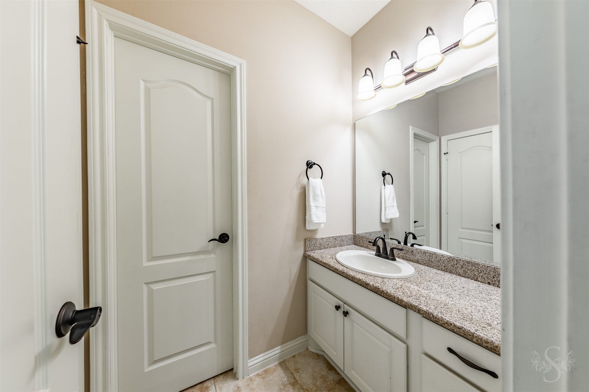 27506 Lakeway Trail Lane, Fulshear, TX 77441 White cabinetry and a polished granite countertop bring timeless appeal to this upstairs vanity area. A large mirror, elegant lighting and dark hardware complete the space with style and everyday convenience.