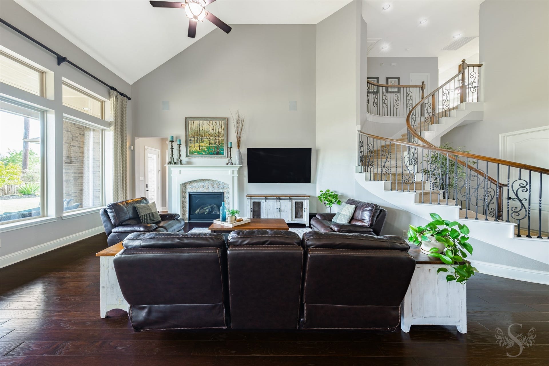 27506 Lakeway Trail Lane, Fulshear, TX 77441 A wall of windows with transoms above fills the spacious family room with backyard views. The fireplaces mosaic tile surround and classic white mantel provide a beautiful focal point, complemented by the sweeping staircase and intricate ironwork.