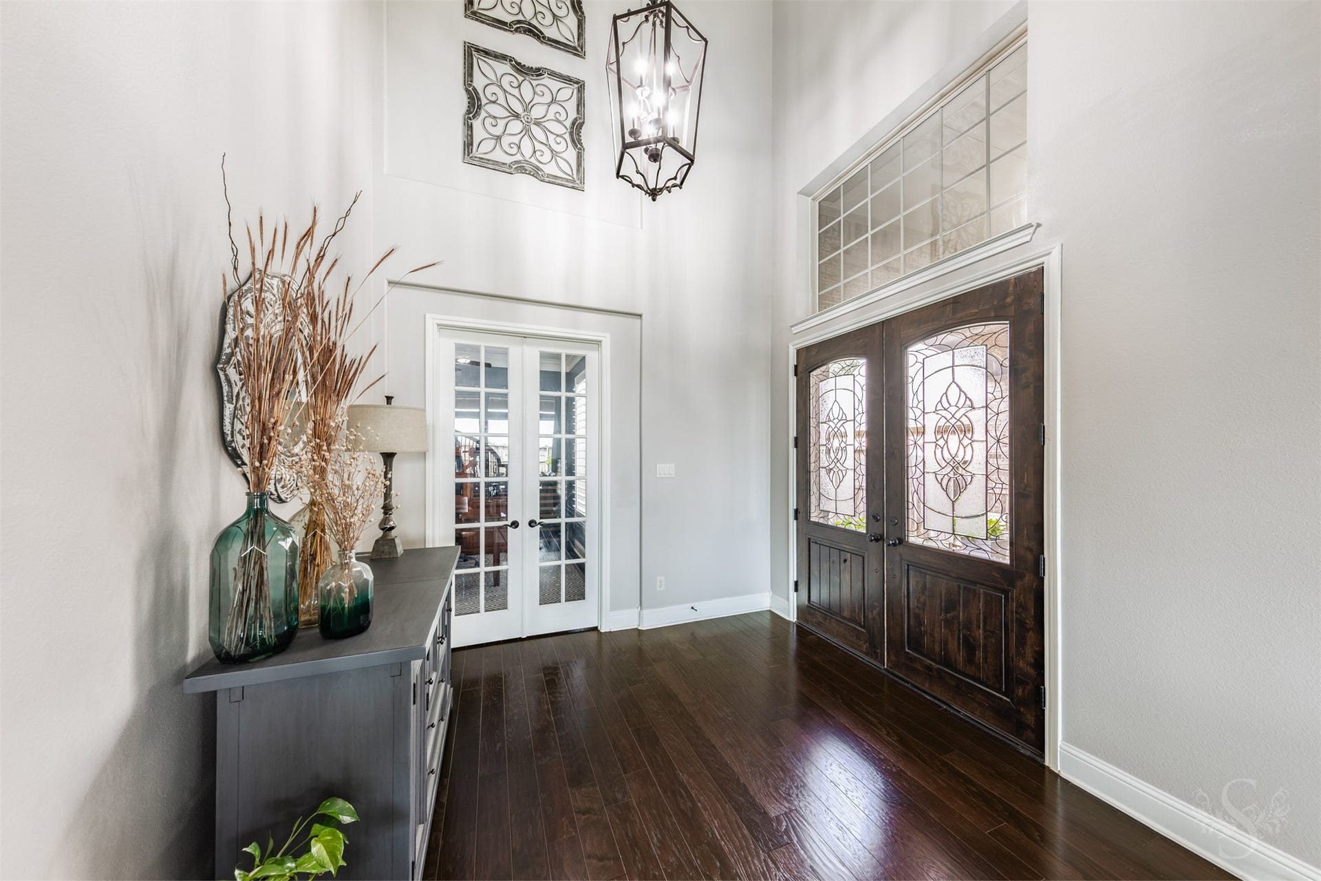 27506 Lakeway Trail Lane, Fulshear, TX 77441 Beautiful double doors with decorative glass open to an impressive entry featuring rich wood flooring and a striking lantern chandelier. A large transom window highlights the entrys impressive height, while French doors introduce the private study.