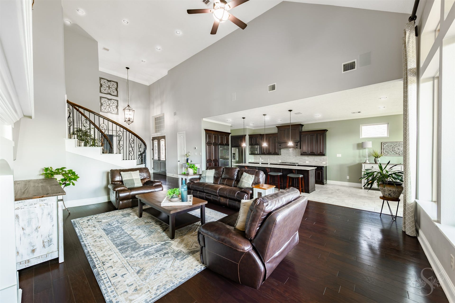 27506 Lakeway Trail Lane, Fulshear, TX 77441 The open concept floor plan showcases a stunning family room with a vaulted ceiling, rich wood flooring and expansive windows. An oversized kitchen island overlooks the gathering space, keeping everyone connected while preparing meals or entertaining friends.
