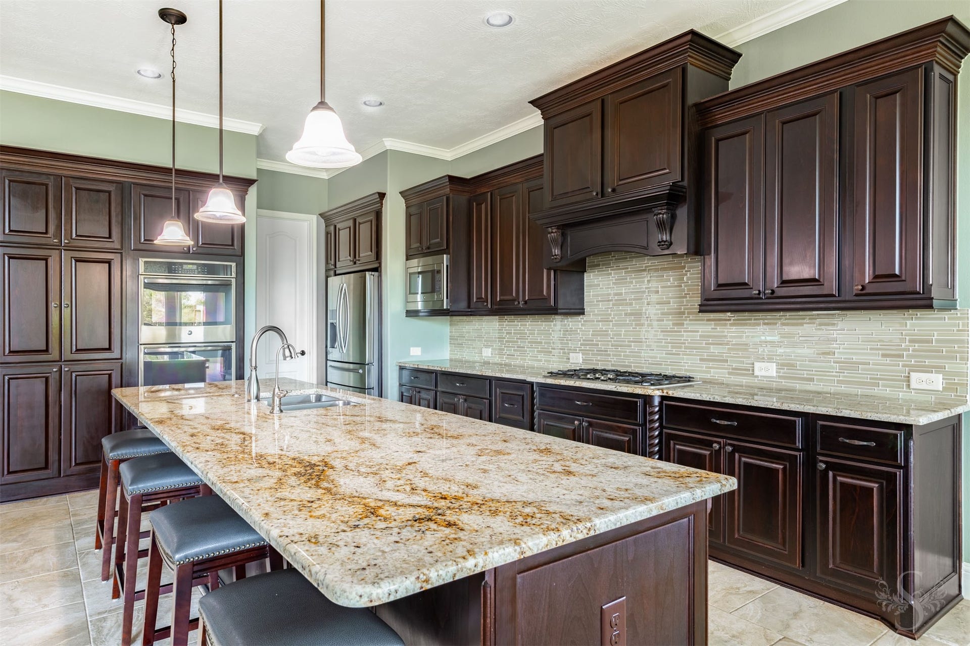 27506 Lakeway Trail Lane, Fulshear, TX 77441 Gorgeous granite stretches across the oversized island, offering abundant workspace and seating for casual meals or conversation with the cook. A gas cooktop, decorative wood vent hood, stainless steel double ovens and extensive cabinetry complete this impressive culinary space.
