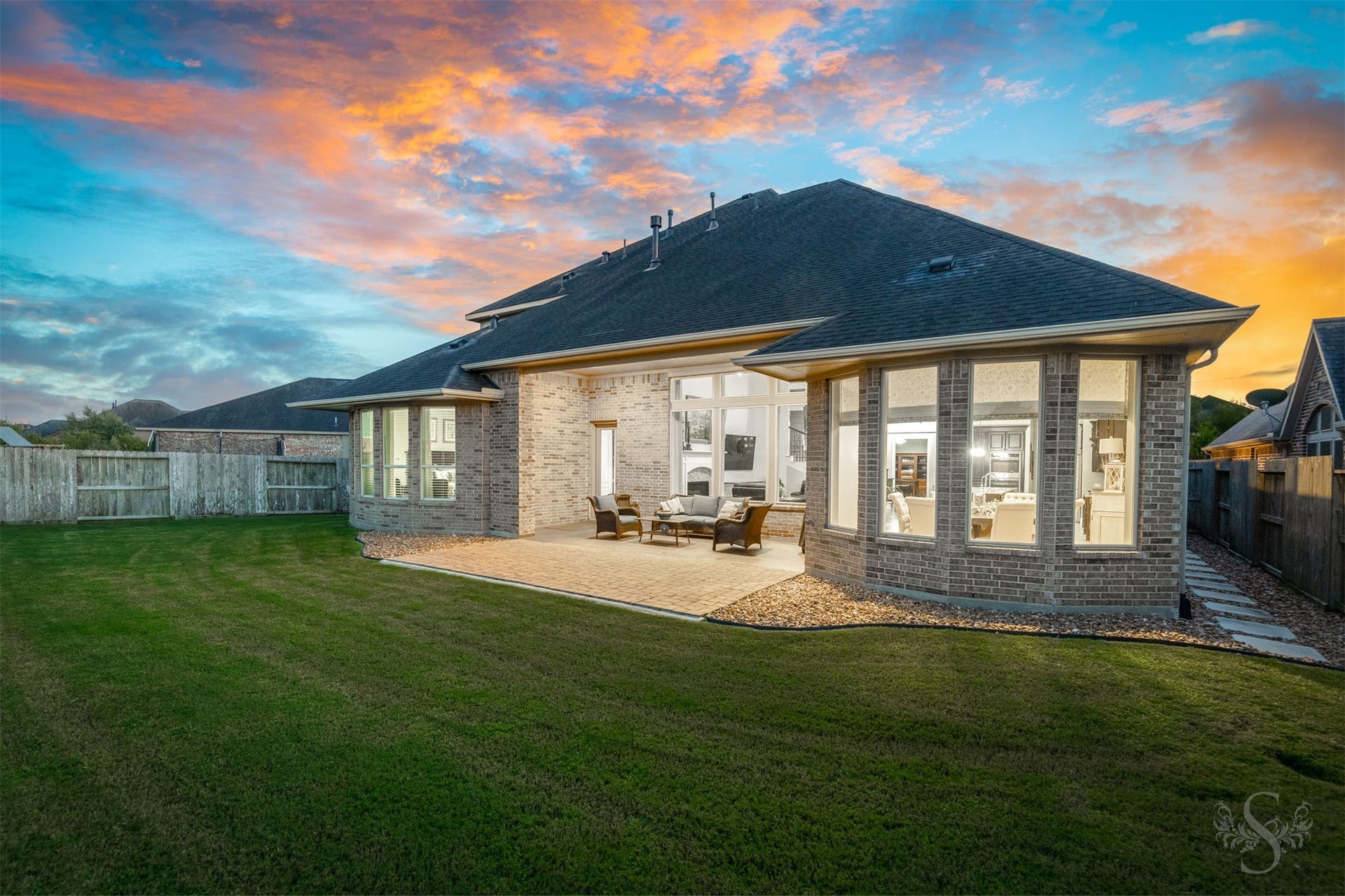 27506 Lakeway Trail Lane, Fulshear, TX 77441 Beautiful bay windows flank the inviting covered patio, creating a striking backdrop for outdoor living. An extended paver patio overlooks the spacious fenced backyard, offering plenty of space for gathering with friends and enjoying time outdoors.