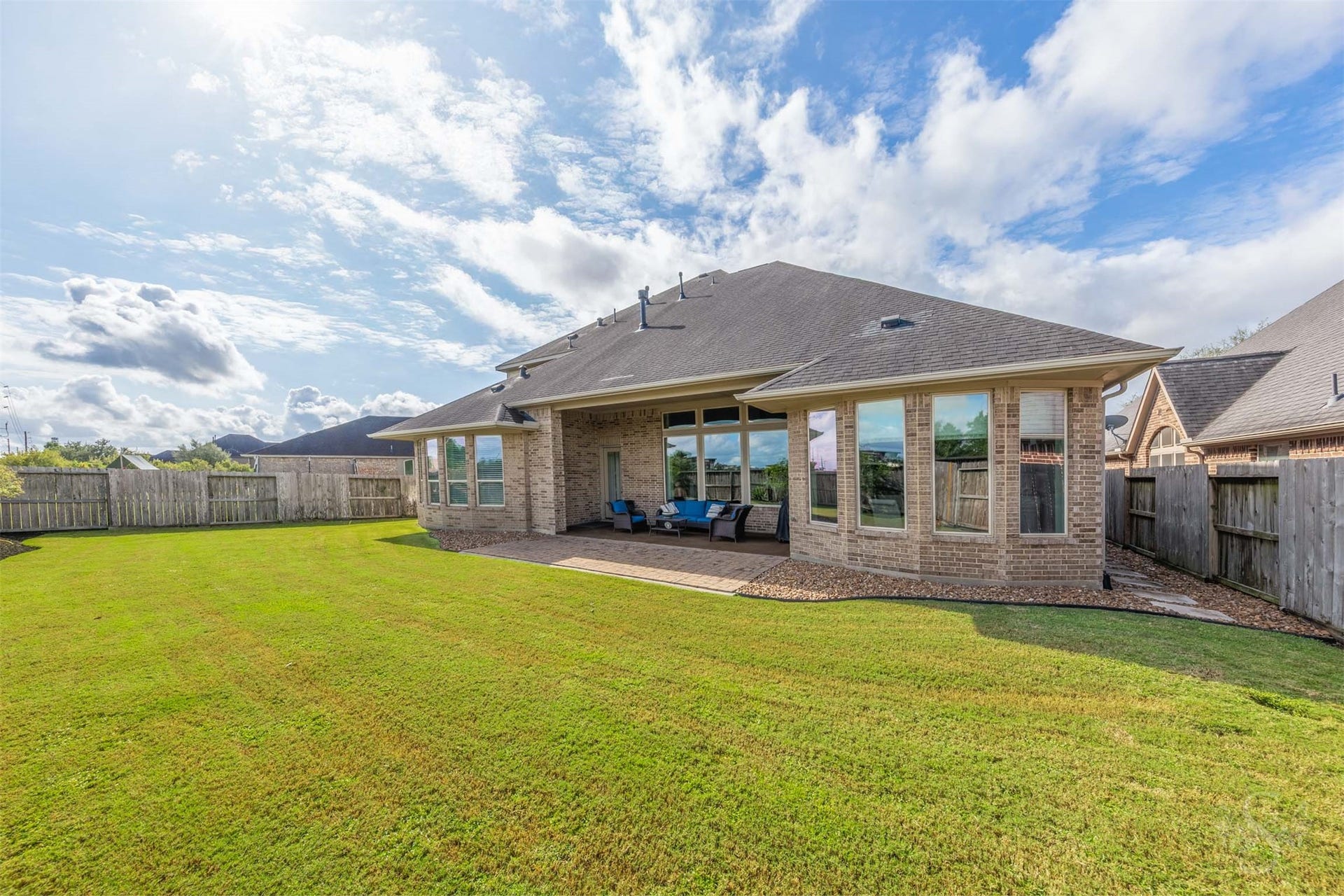 27506 Lakeway Trail Lane, Fulshear, TX 77441 Beautiful bay windows flank the inviting covered patio, creating a striking backdrop for outdoor living. An extended paver patio overlooks the spacious fenced backyard, offering plenty of space for gathering with friends and enjoying time outdoors.
