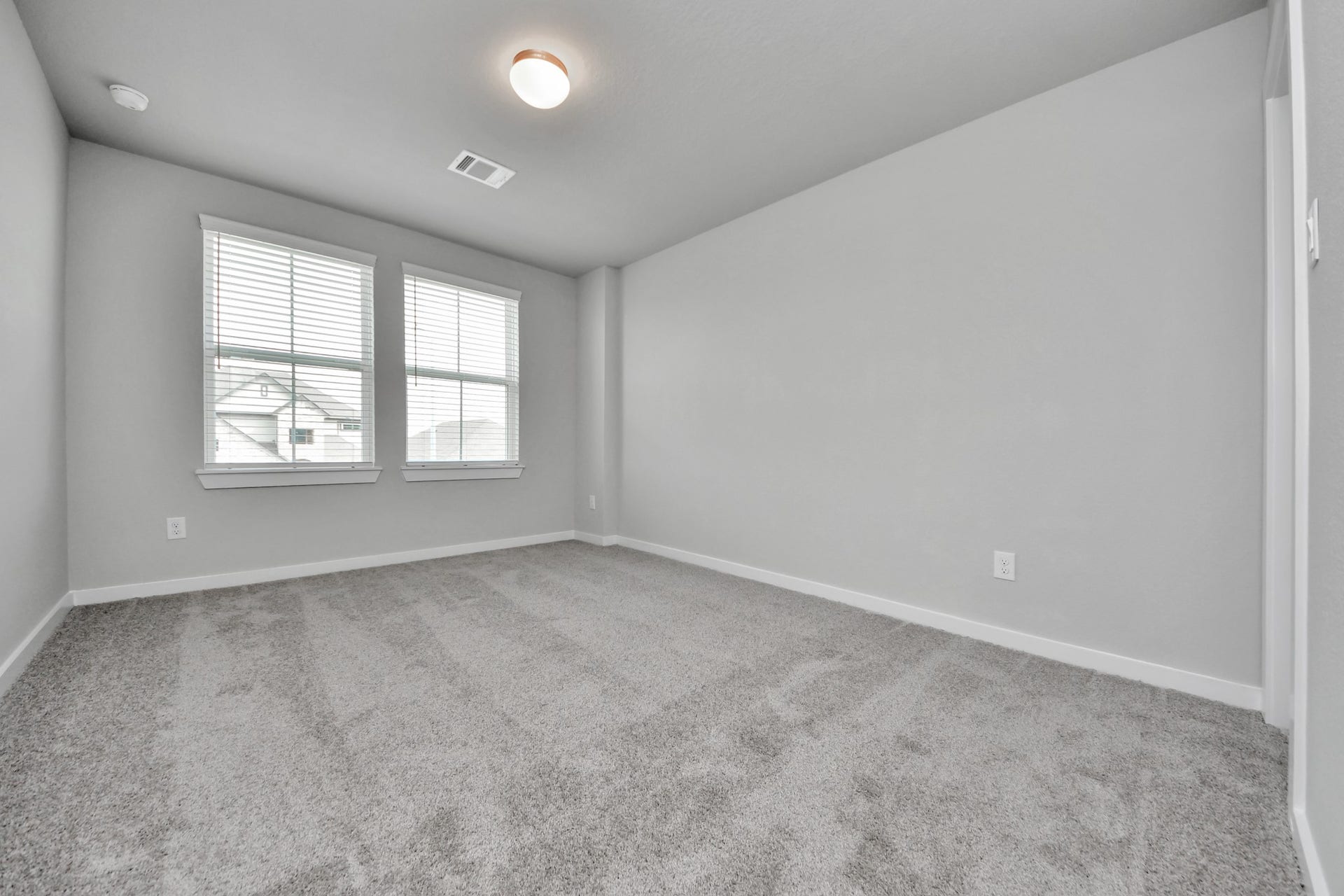 Secondary bedroom features plush carpeting, large windows that let in plenty of natural light, bright paint, and spacious closets. Sample photo of completed home with similar floor plan. Actual colors and selections may vary.