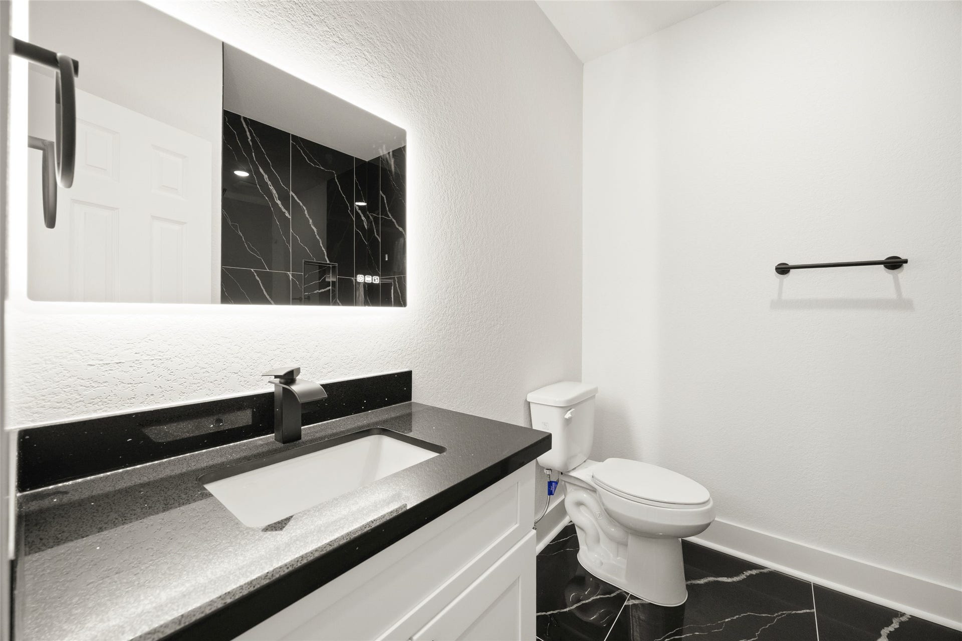 Sleek and modern bathroom featuring a chic black marble countertop, stylish black fixtures, and striking black tile flooring.