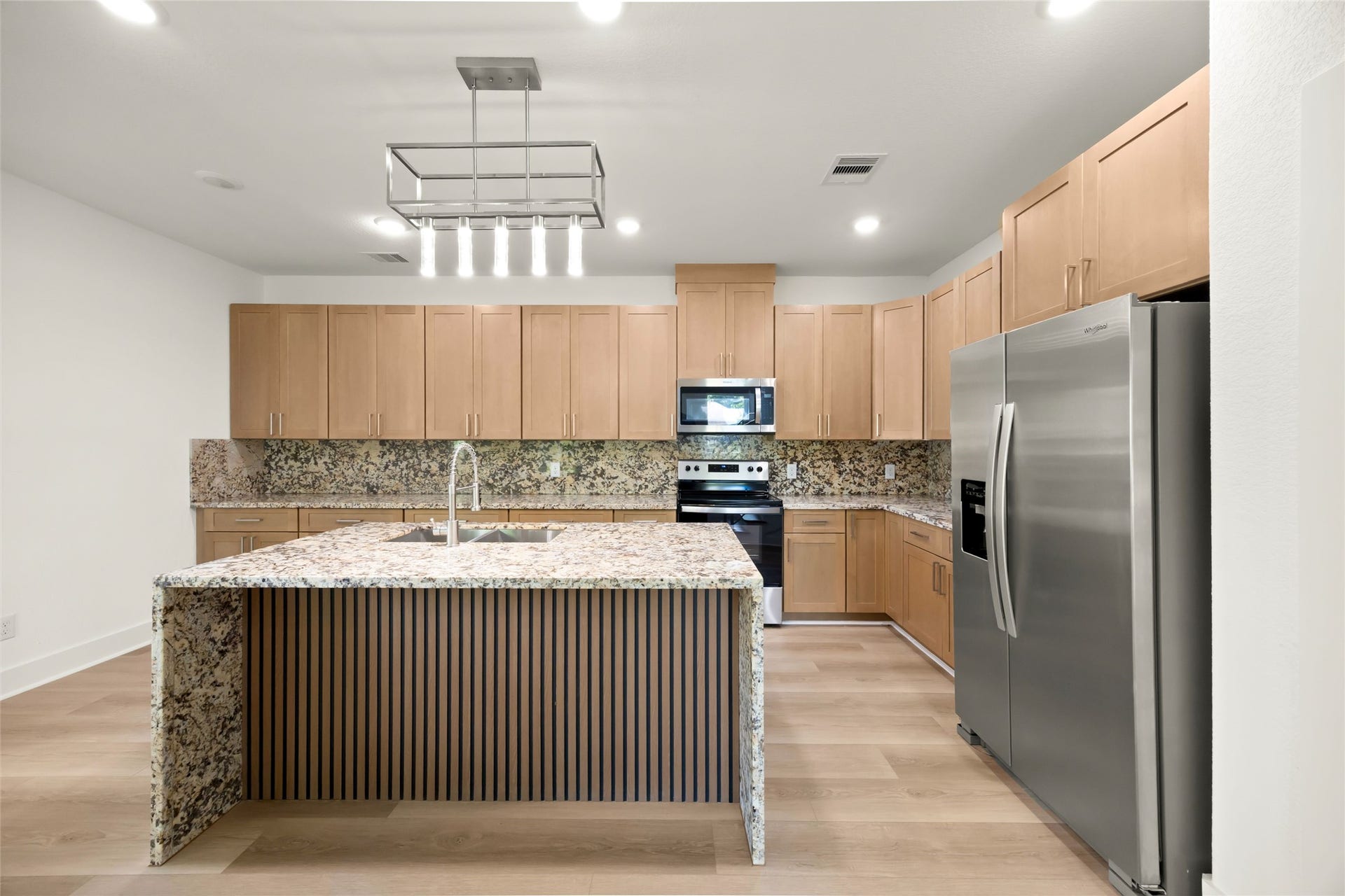 Modern kitchen featuring sleek stainless steel appliances, elegant granite countertops, and ample wooden cabinetry for a warm, inviting atmosphere.
