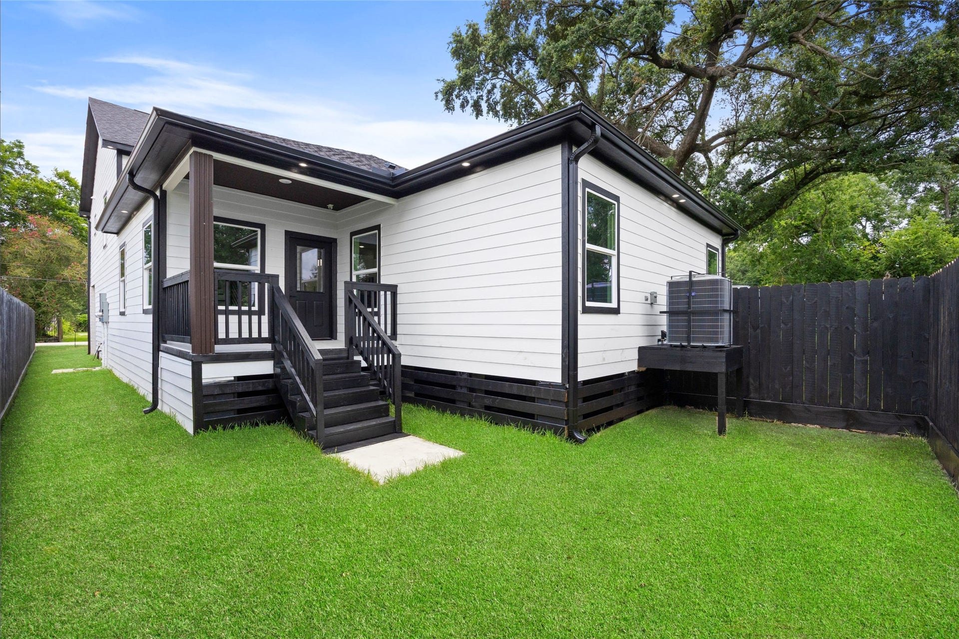 Charming modern exterior with a cozy porch, set against a spacious, well-maintained backyard enclosed by a privacy fence.