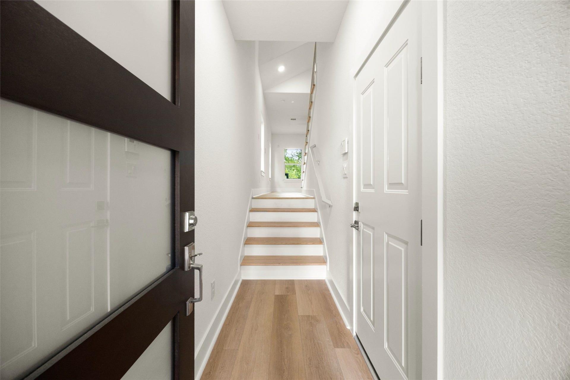 Bright and inviting, this entryway features sleek wood flooring and modern finishes, leading to a staircase that opens into the main living space.