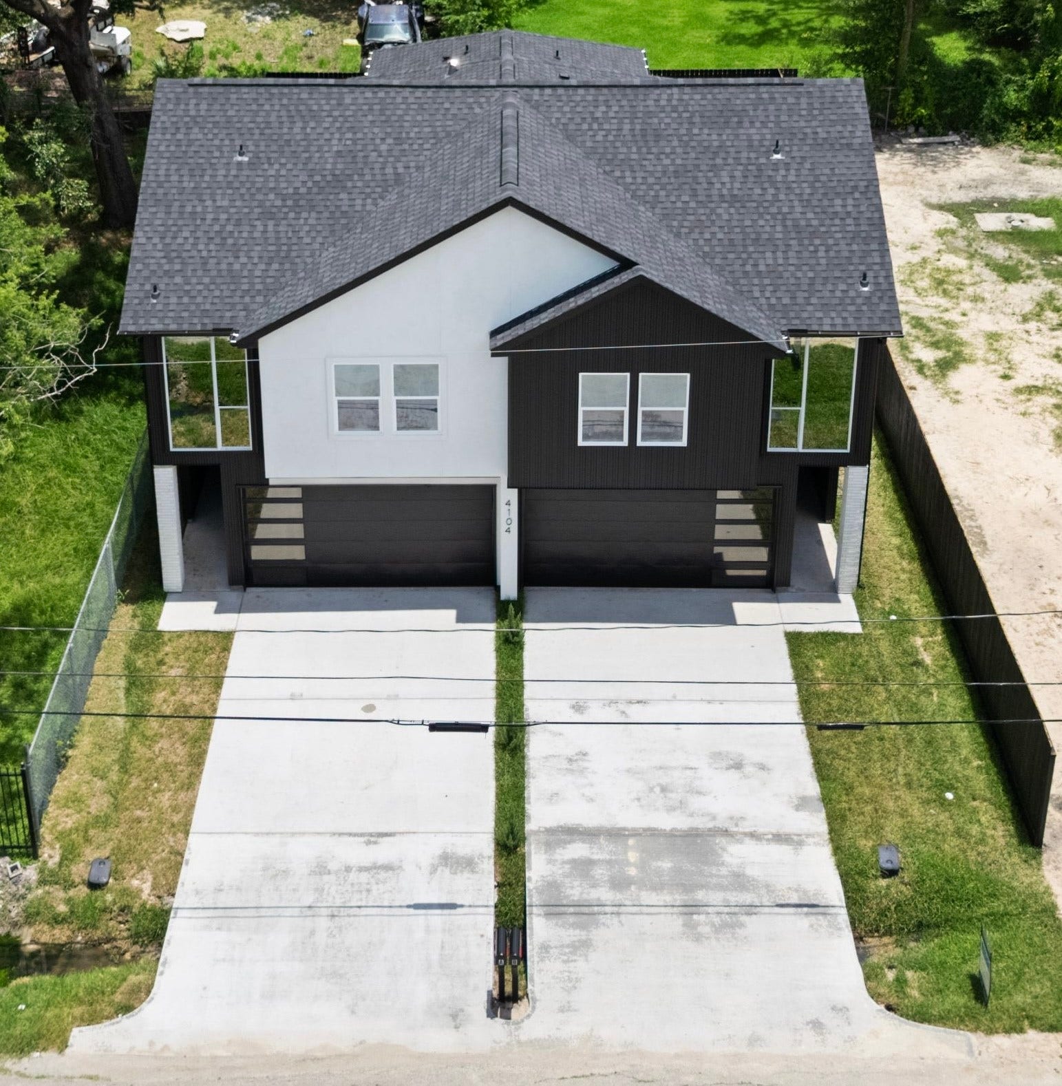 Modern duplex nestled in a lush, green setting, featuring sleek design and spacious driveways, offering privacy and tranquility.