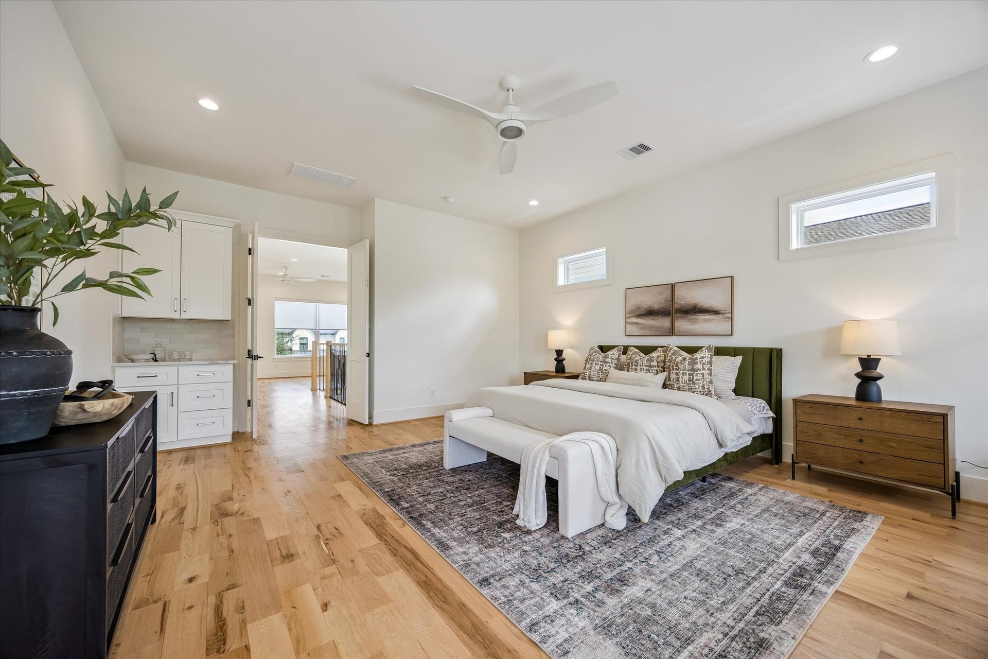 The primary suite welcomes you through elegant double French doors, with gorgeous hardwood floors and a custom credenza topped with a sophisticated countertop.
