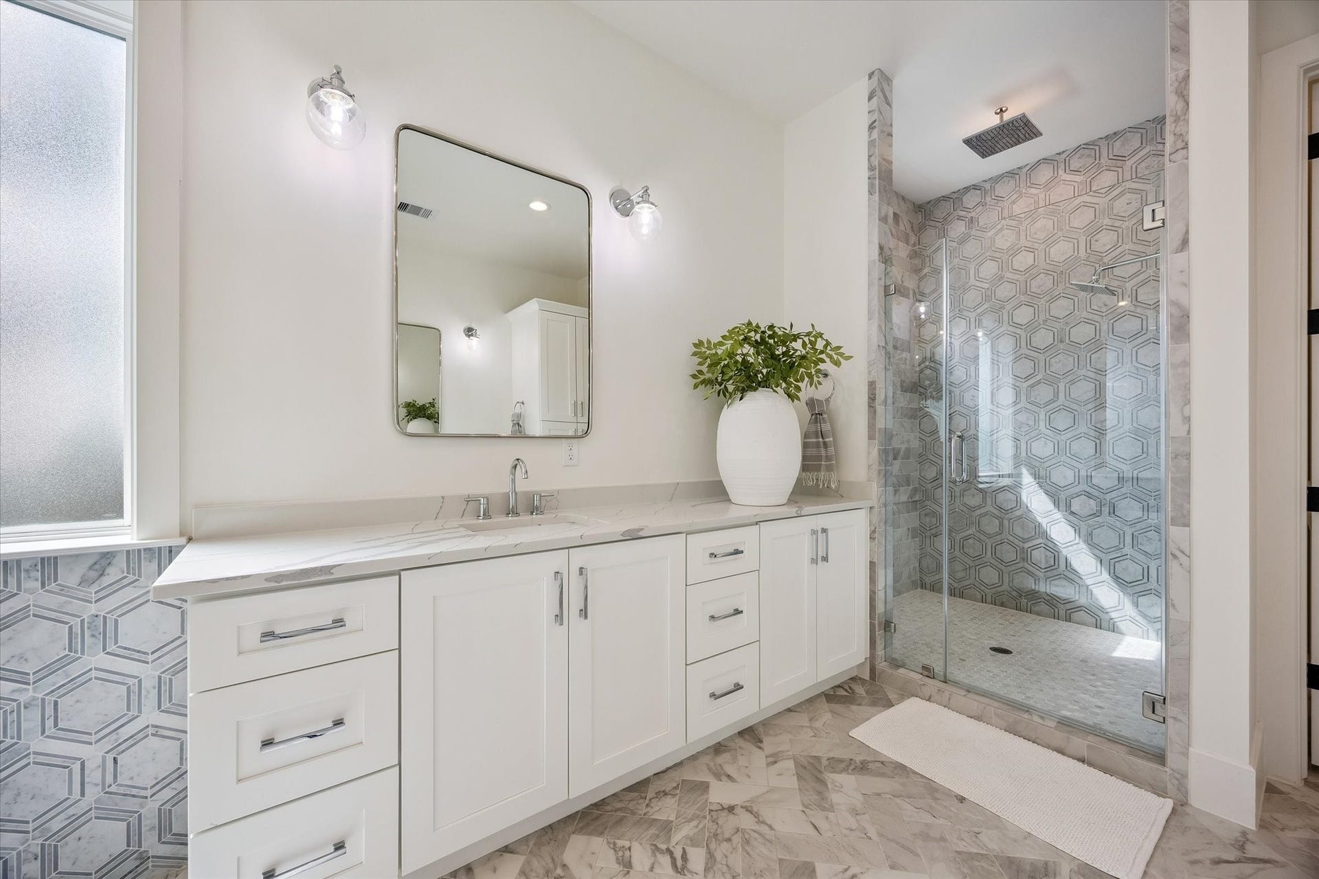 The luxurious primary bathroom features elegant marble floors and separate vanities, creating a refined and relaxing retreat.