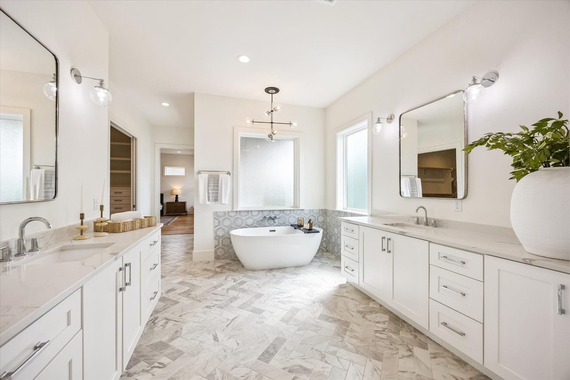 A light, airy color palette, abundant natural light and sleek silver modern finishes complete the sophisticated look of the primary bathroom.