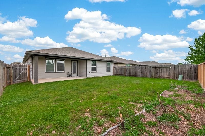 7523 Keystone Blossom Trail, Richmond, TX 77407 Wide rear exterior view showcasing the homes full back elevation, covered patio, and an expansive fenced yard with open green space.