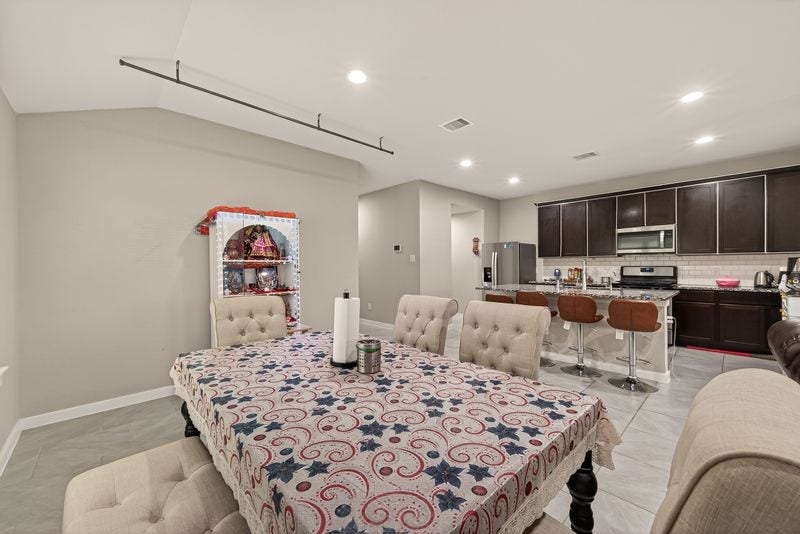 7523 Keystone Blossom Trail, Richmond, TX 77407 Alternate view of the dining area flowing into the kitchen, emphasizing the expansive wall space, overhead lighting, and continuity of the open layout.