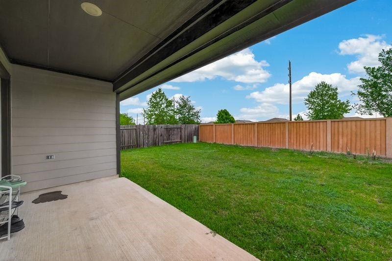 7523 Keystone Blossom Trail, Richmond, TX 77407 Alternate view from the patio showcasing the full span of the backyard, with continuous fencing and an expansive lawn extending across the property.